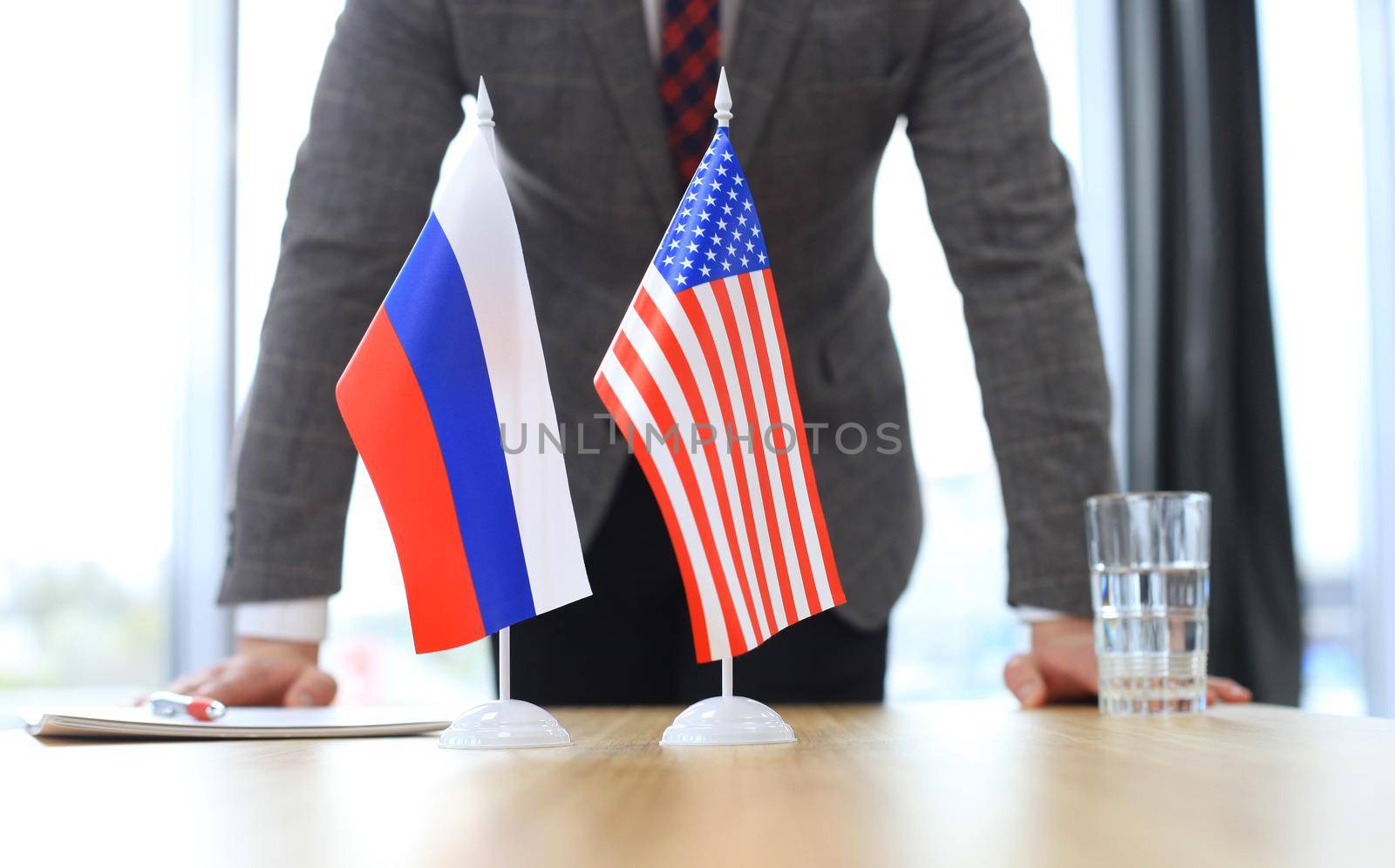Russian flag and flag of European Union with businessman near by