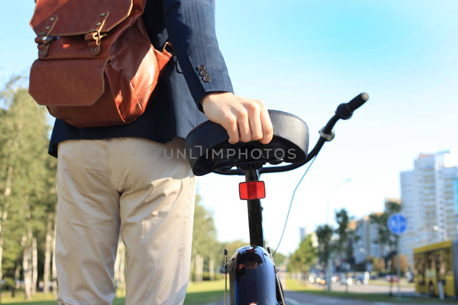 Confident young businessman walking with bicycle on the street in town.