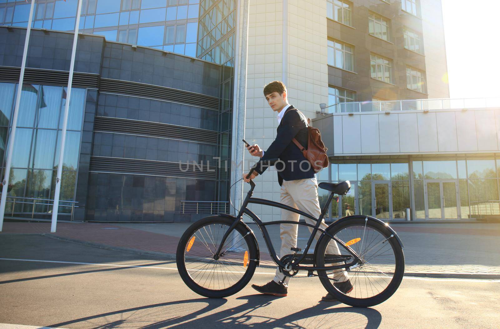 Confident young businessman walking with bicycle on the street in town.