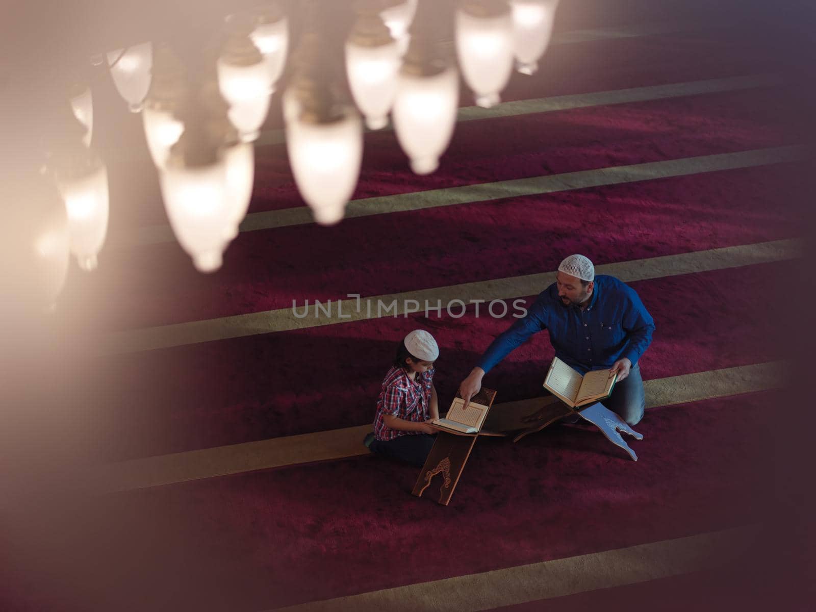 father and son in mosque praying and reading holly book quran together by dotshock