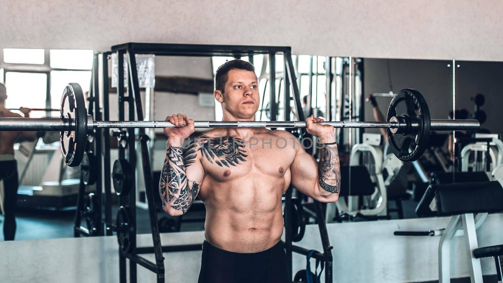 muscular young man performing exercises with a barbell. Sport, commitment, motivation