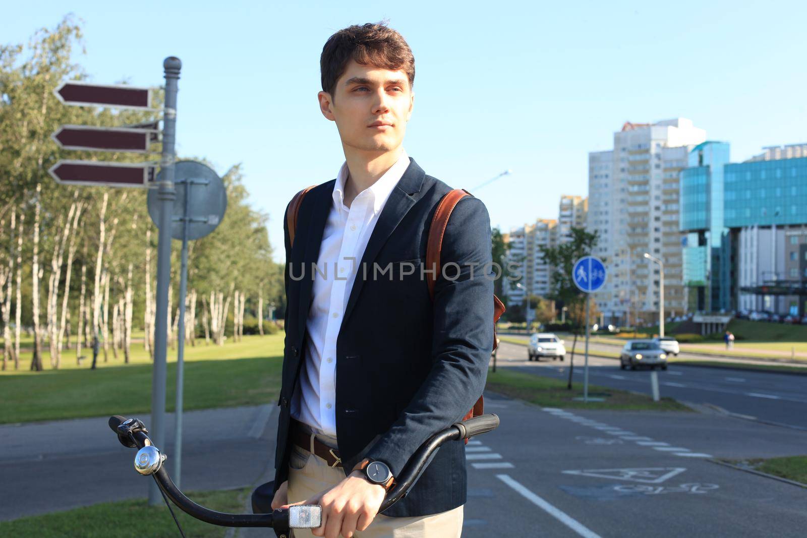 Confident young businessman walking with bicycle on the street in town.