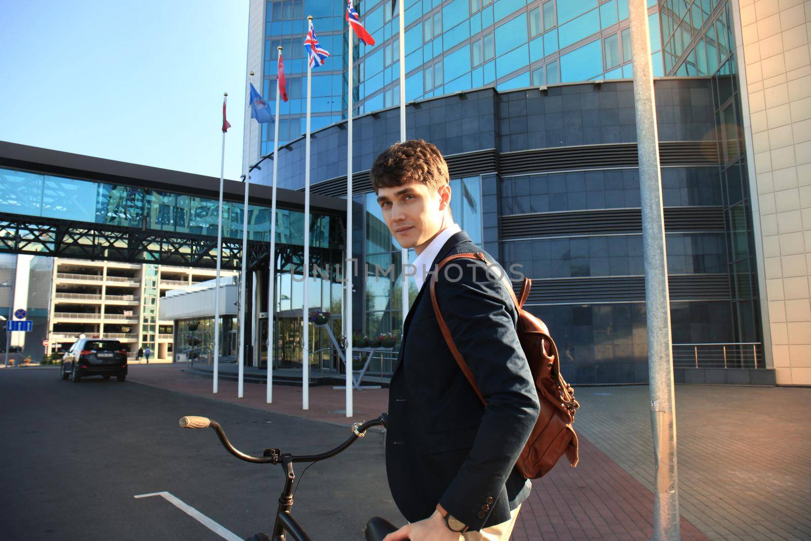 Confident young businessman walking with bicycle on the street in town.