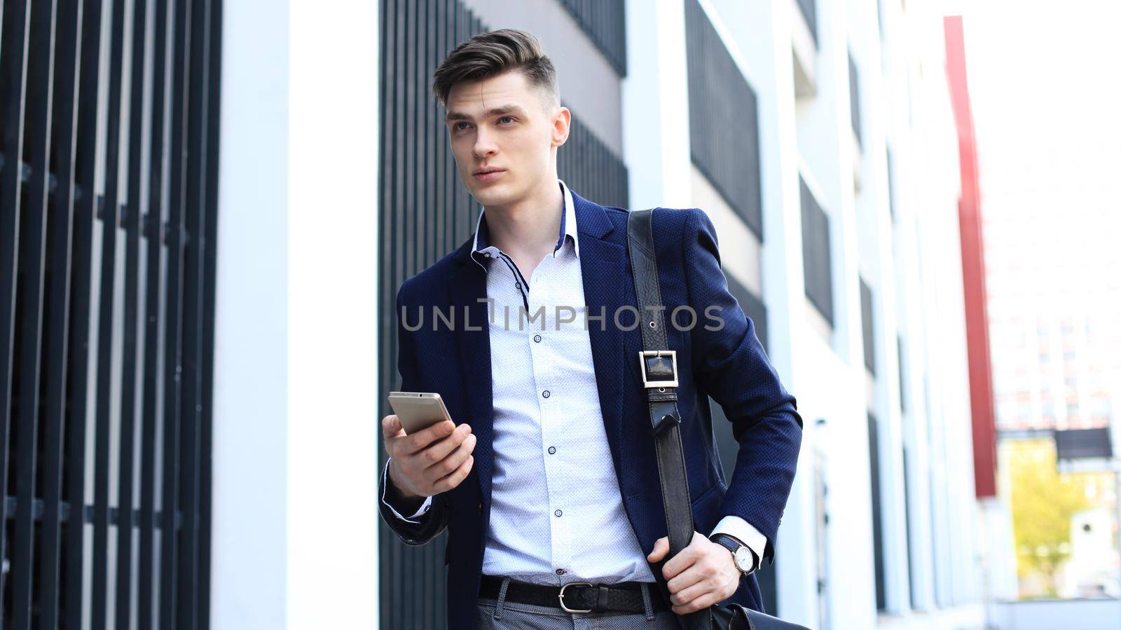 Young urban businessman professional on smartphone walking in street using mobile phone