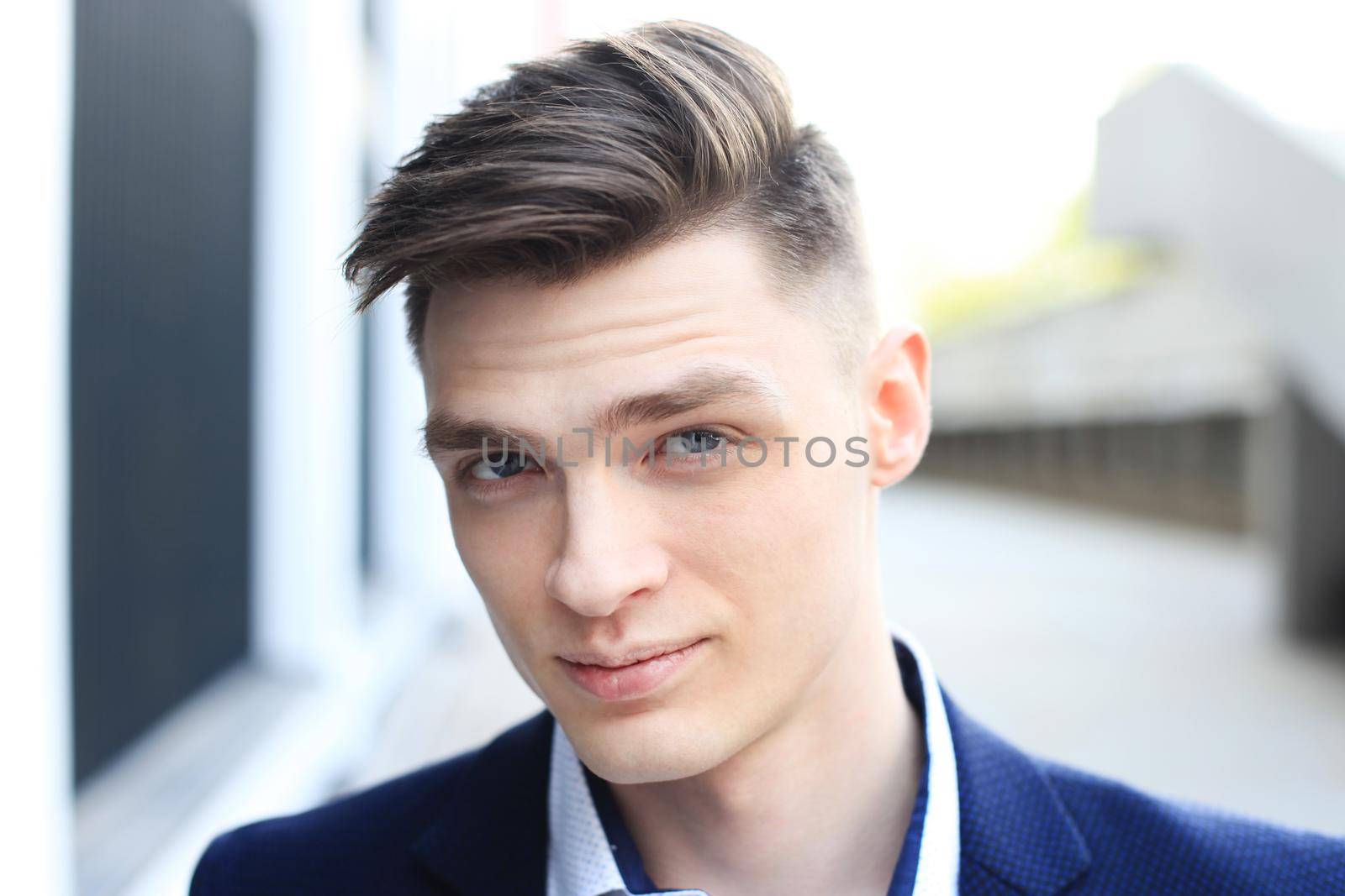 Portrait of a handsome businessman in a suit standing outside a city building