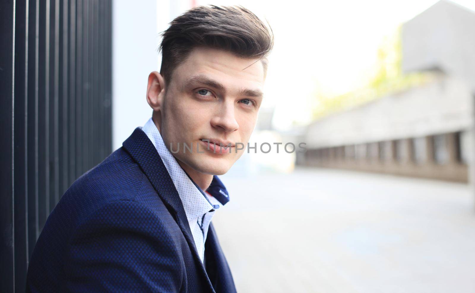 Portrait of a handsome businessman in a suit standing outside a city building