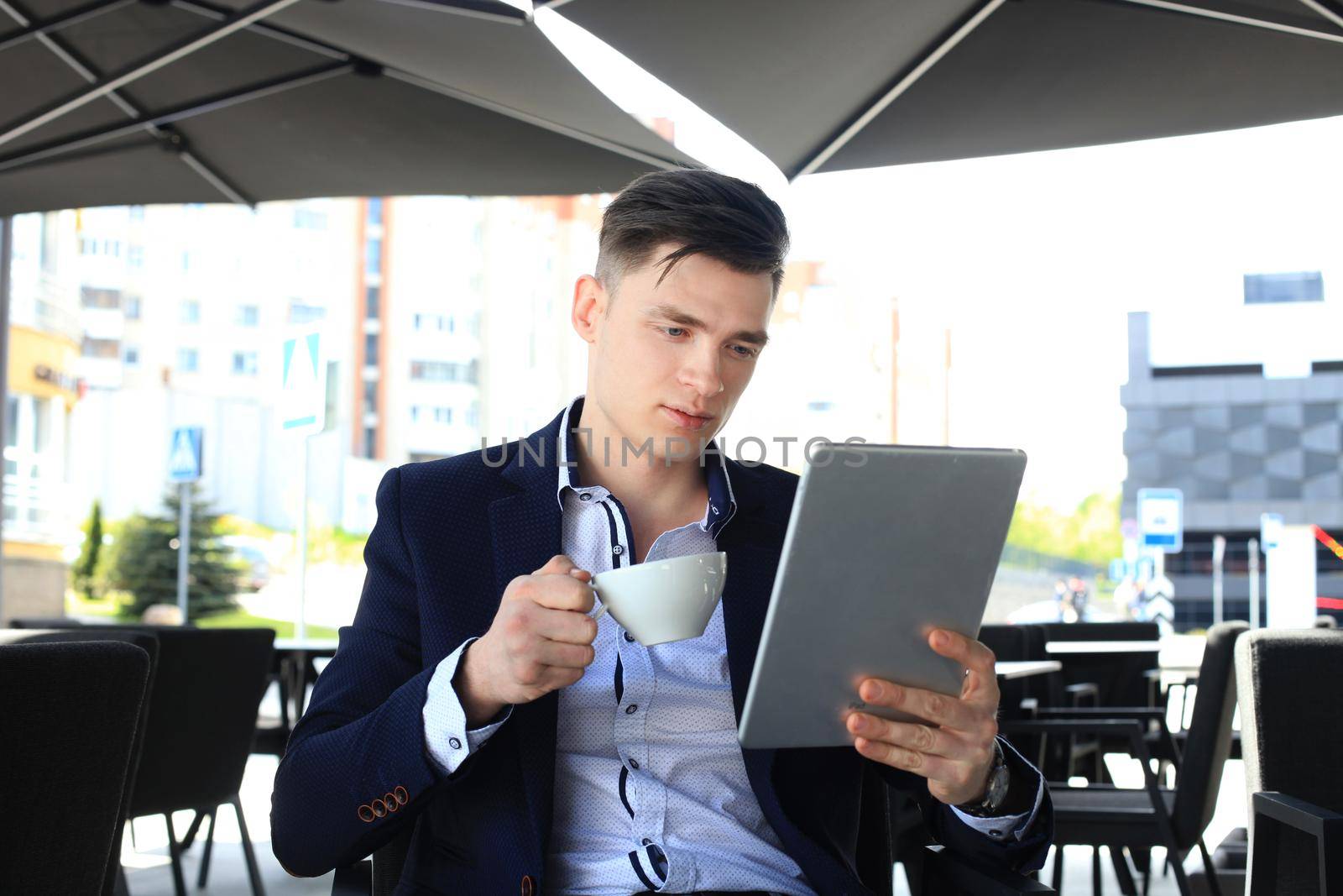 Businessman drinking coffee and reading news in cafe.