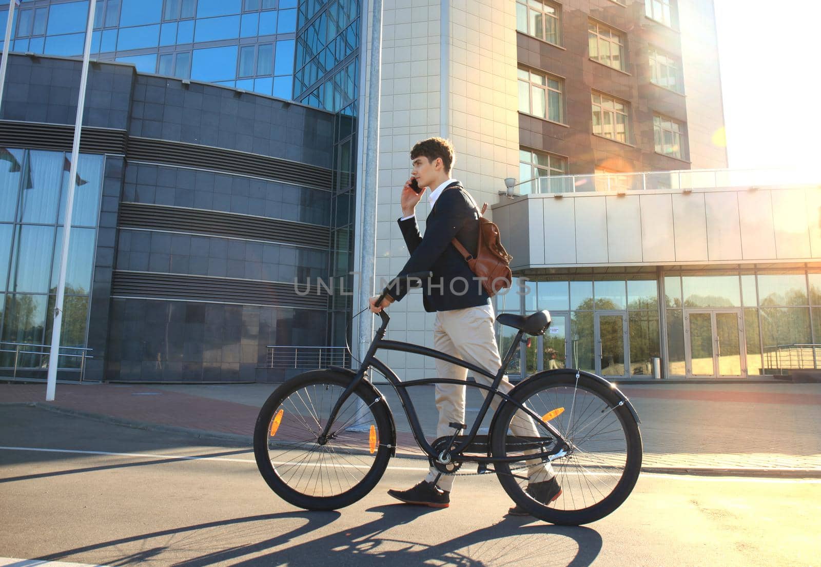 Young businessman with bicycle and smartphone on city street.