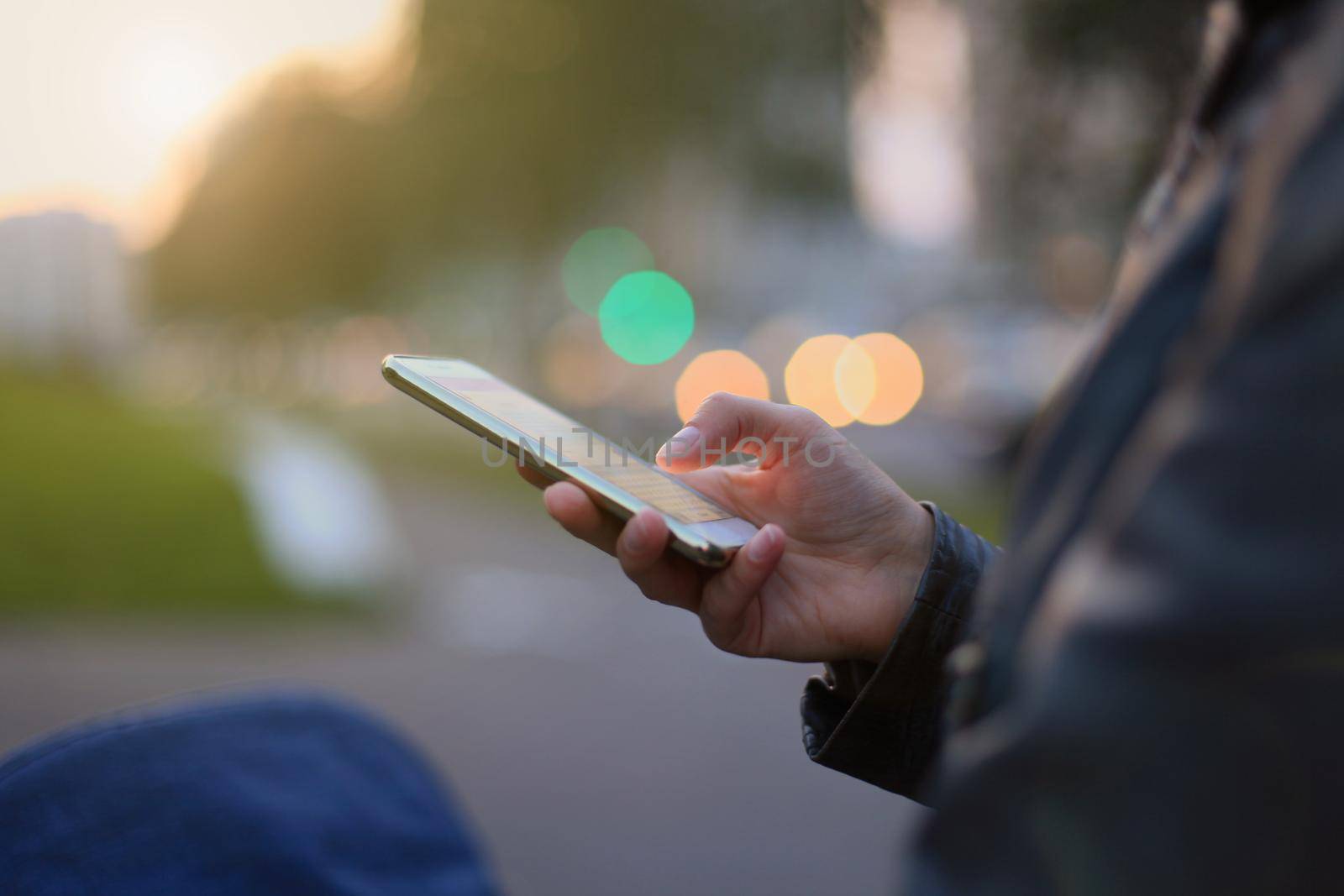 Closeup of female hand holding modern smartphone with blank screen, display at night city.