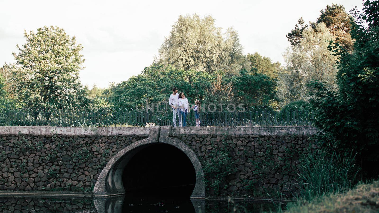view from afar.parents with their little daughter standing on the bridge. travel together