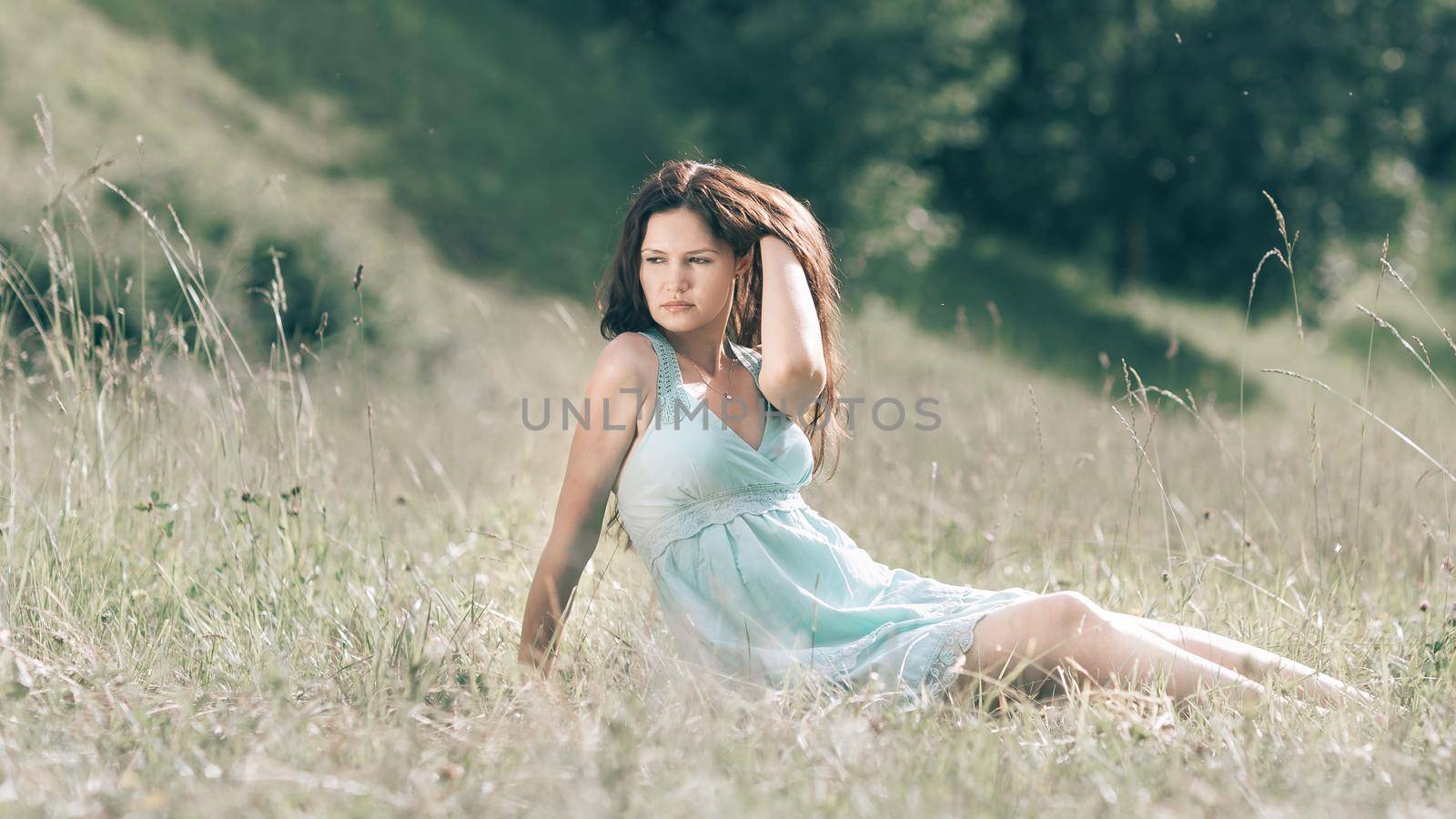 brooding young woman sitting on the grass of a summer meadow.photo with copy space