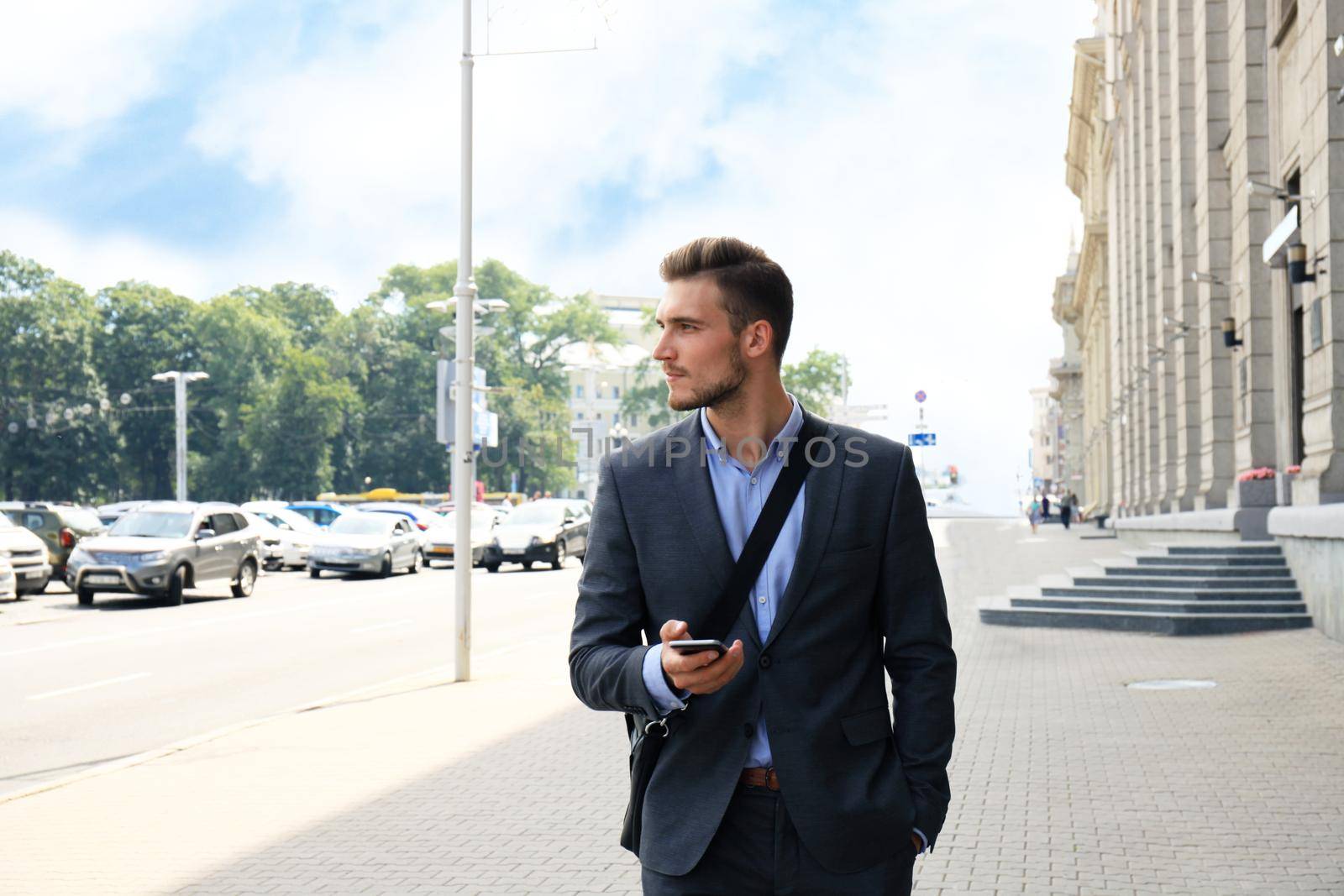 Young urban businessman professional on smartphone walking in street using mobile phone.