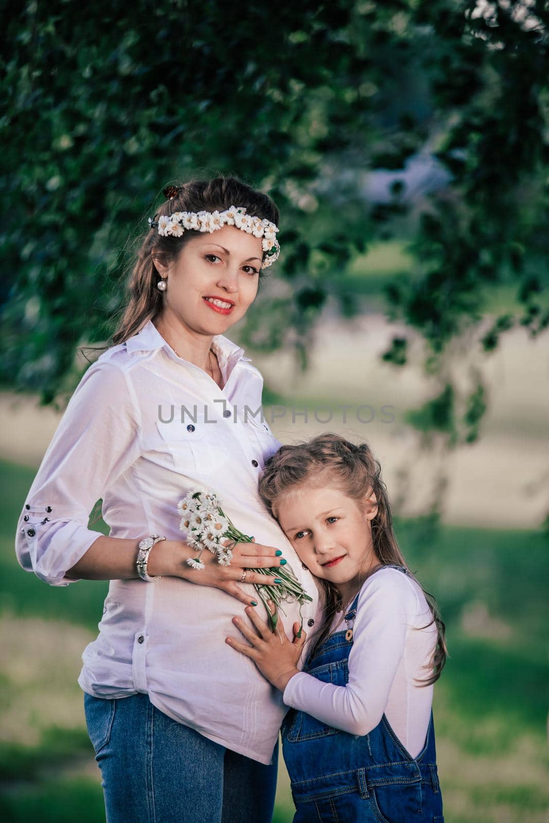 happy pregnant mom with her little daughter for a walk on a summer day.good time