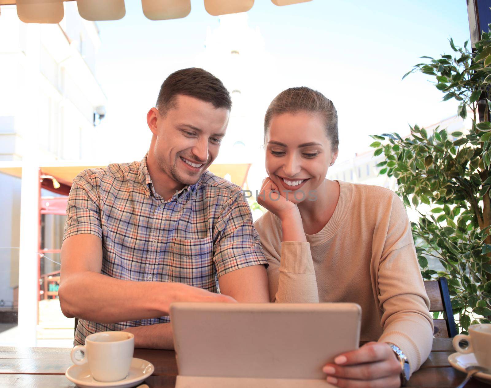 Flirting couple in cafe using digital tablet.