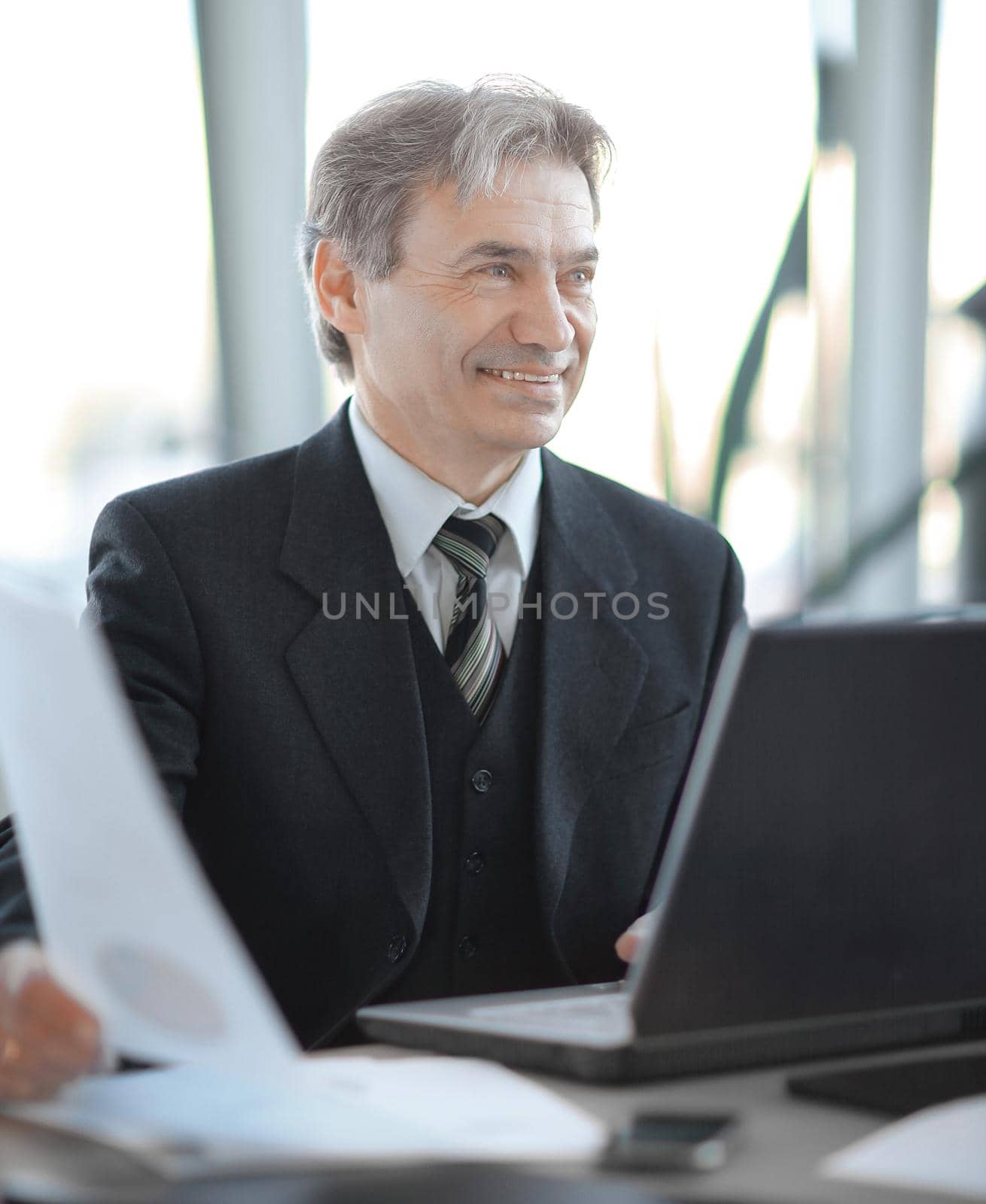 closeup. smiling senior businessman sitting at his Desk