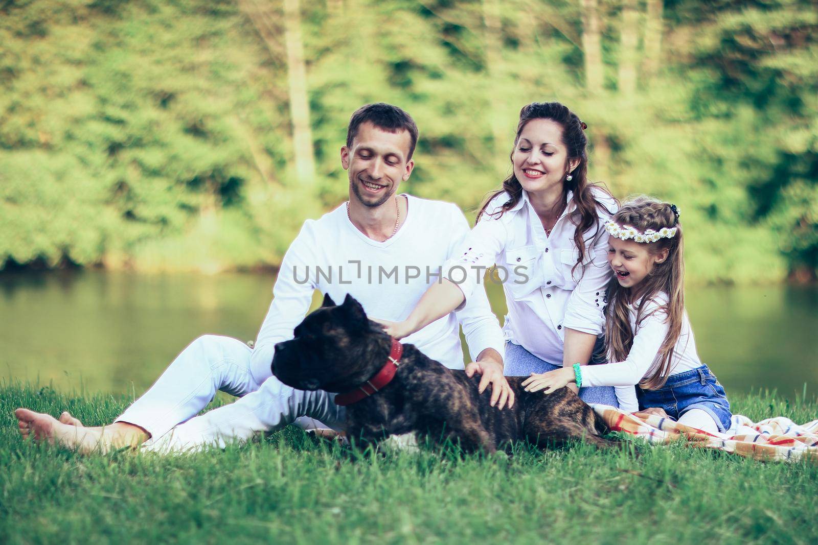 ,little daughter and their dog on a picnic by the river.the photo has a space for your text