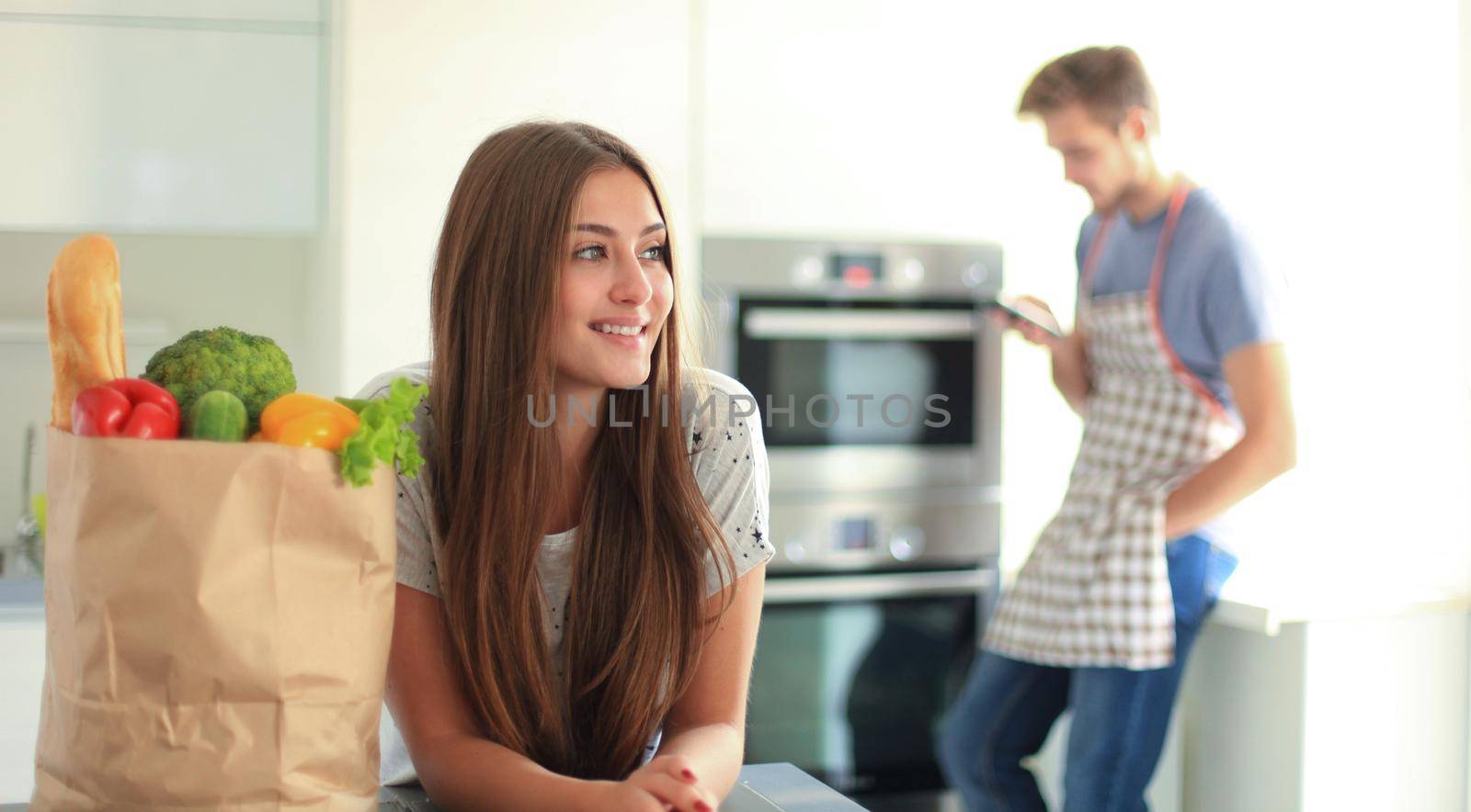 Young couple in the kitchen , woman with a bag of groceries shopping by tsyhun