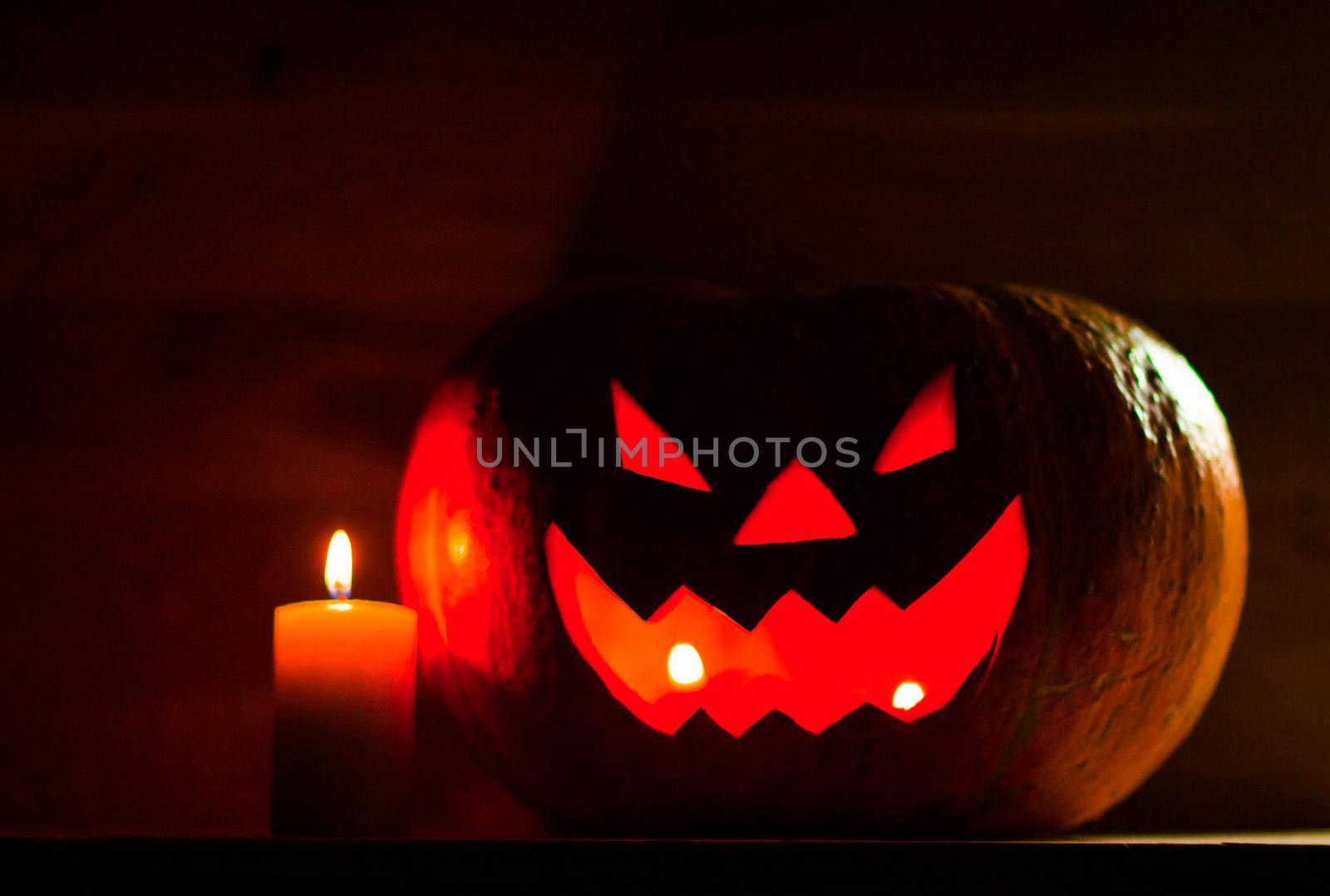 candle and creepy smiling pumpkin for Halloween on black background