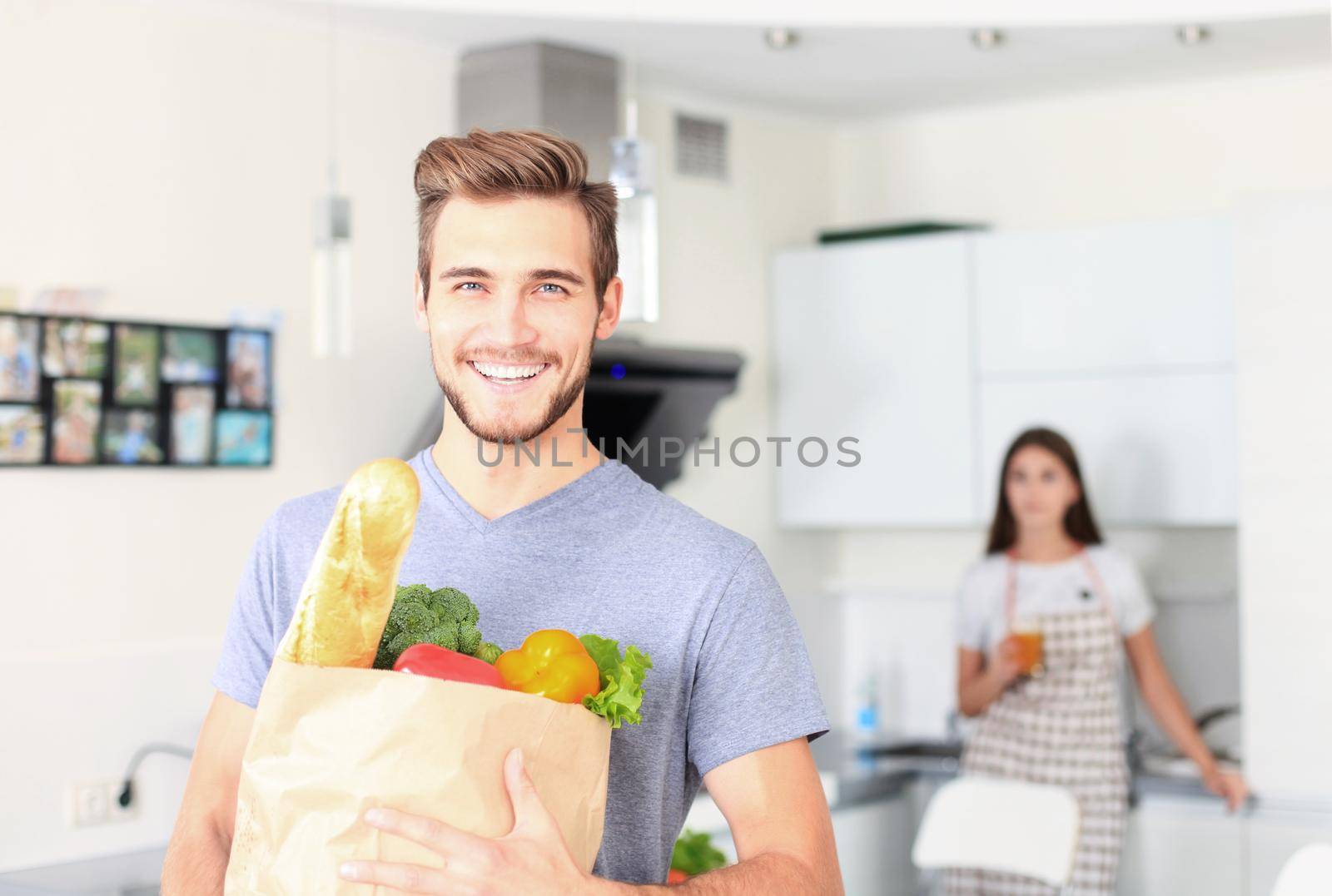 Young couple in the kitchen , man with a bag of groceries shopping by tsyhun