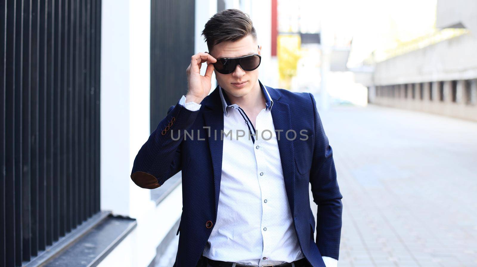 handsome stylish man in elegant suit and sunglasses in the street