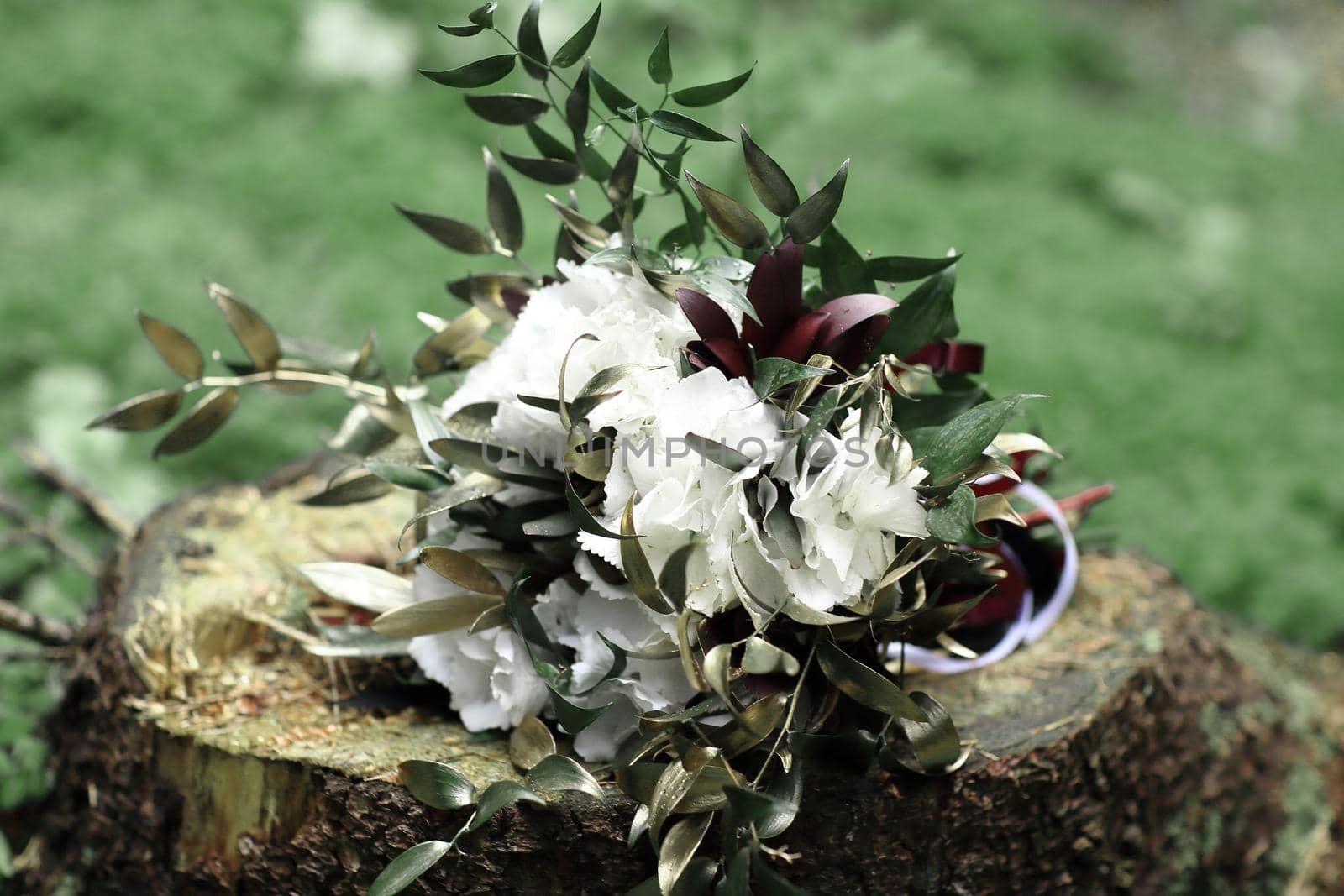 close up.flower arrangement on a stump on the grass background.