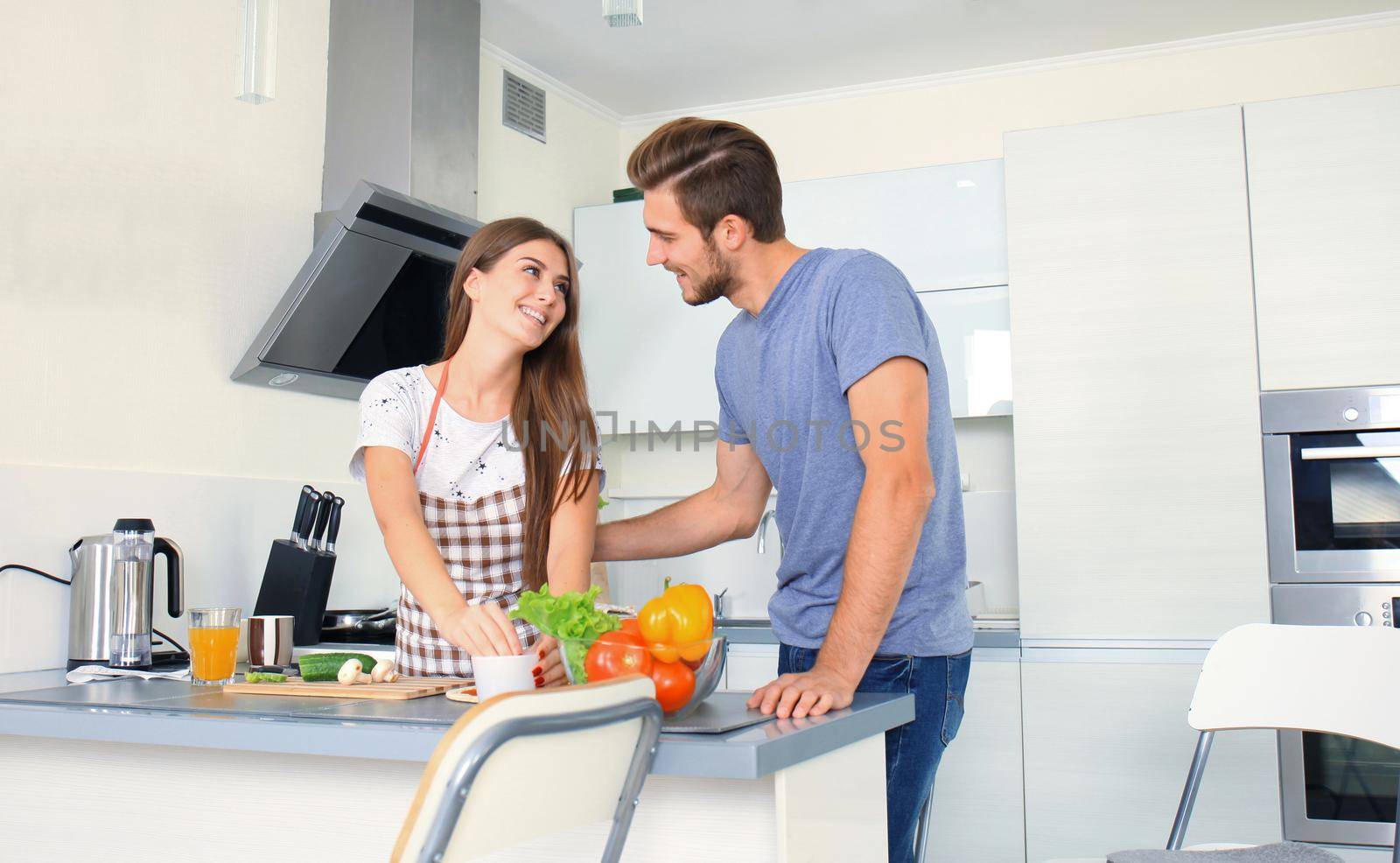 Portrait of happy young couple cooking together in the kitchen at home.