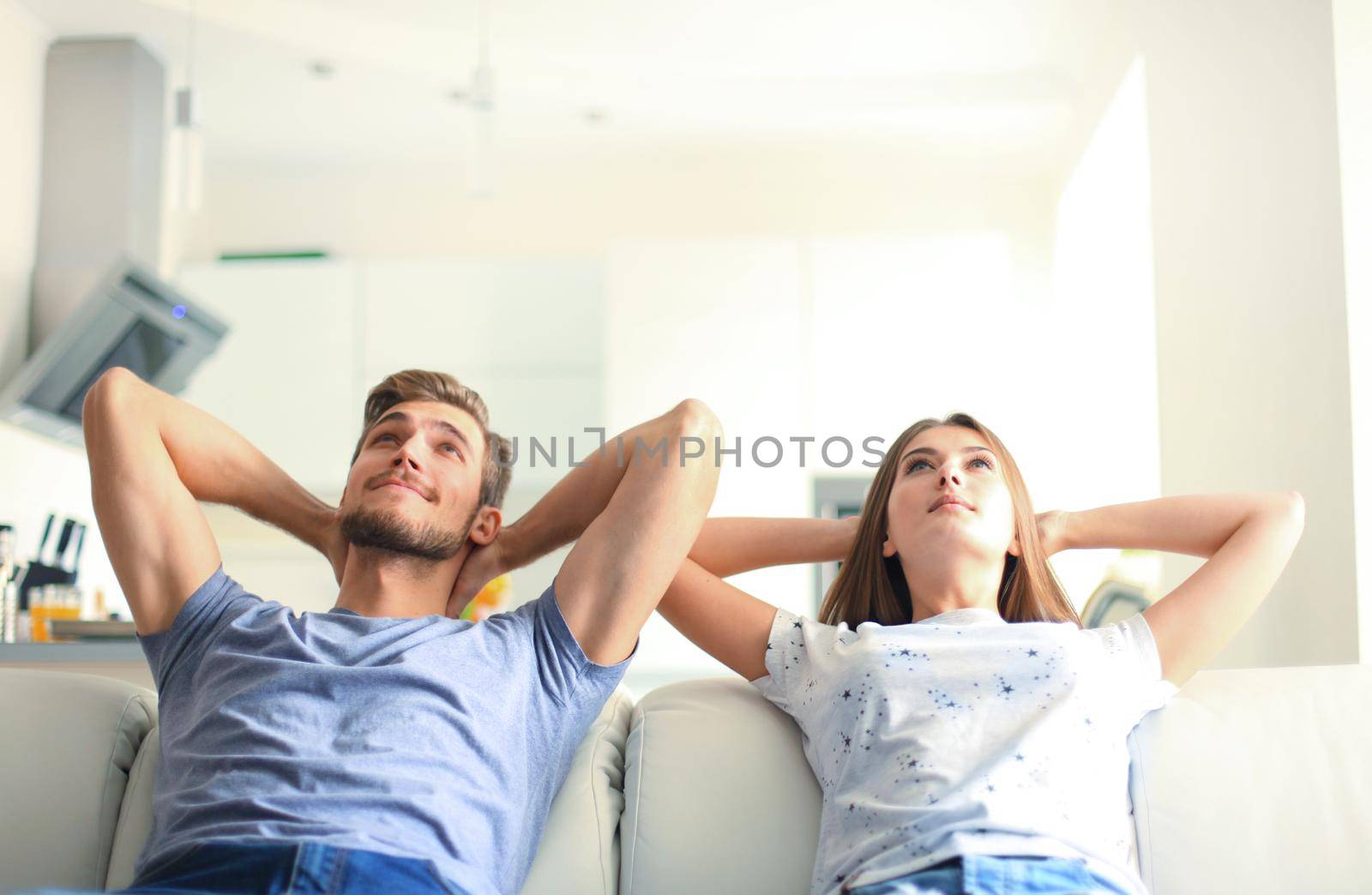 Smiling beautiful couple sitting on a sofa and dreaming about new home.