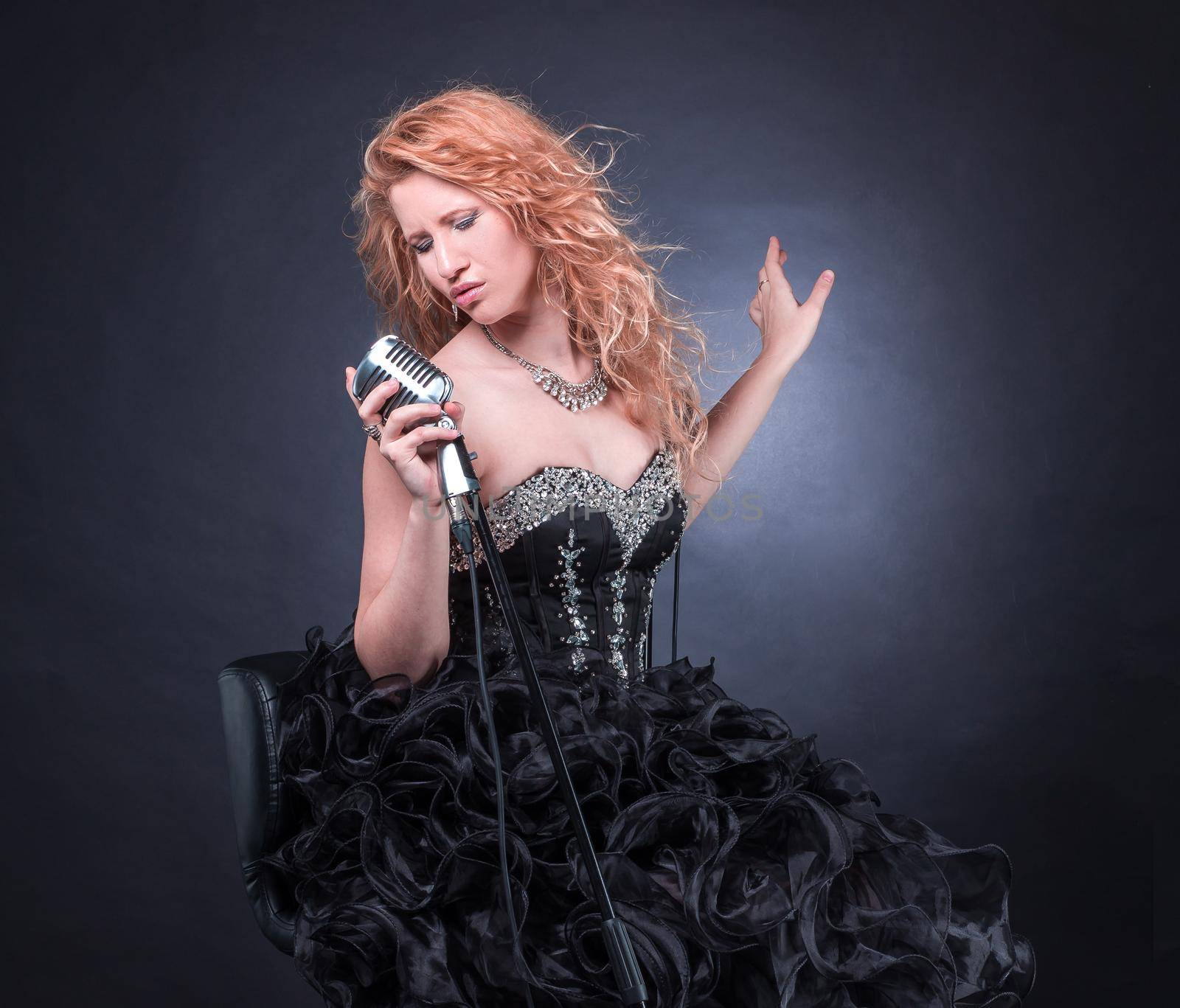 beautiful female singer in black concert dress performing jazz. isolated on a dark