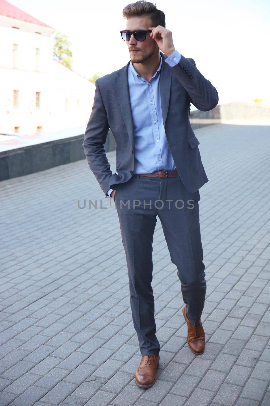 handsome stylish man in elegant suit and sunglasses in the street.