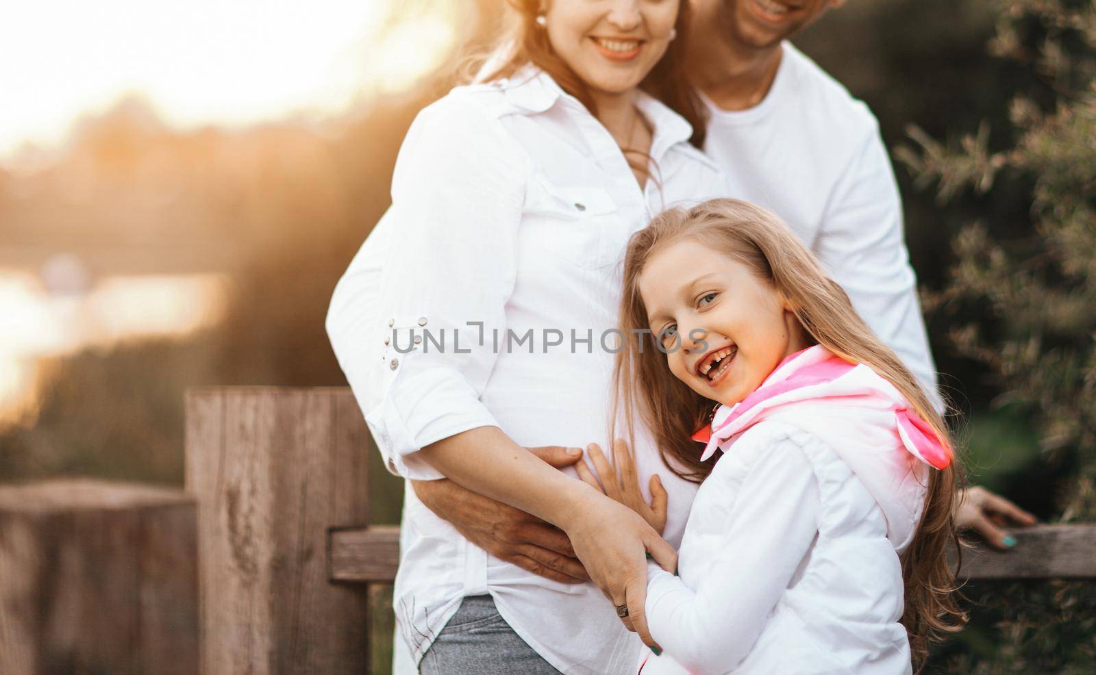 pregnant mom,happy father and little daughter on a walk in the Park on a Sunny day.