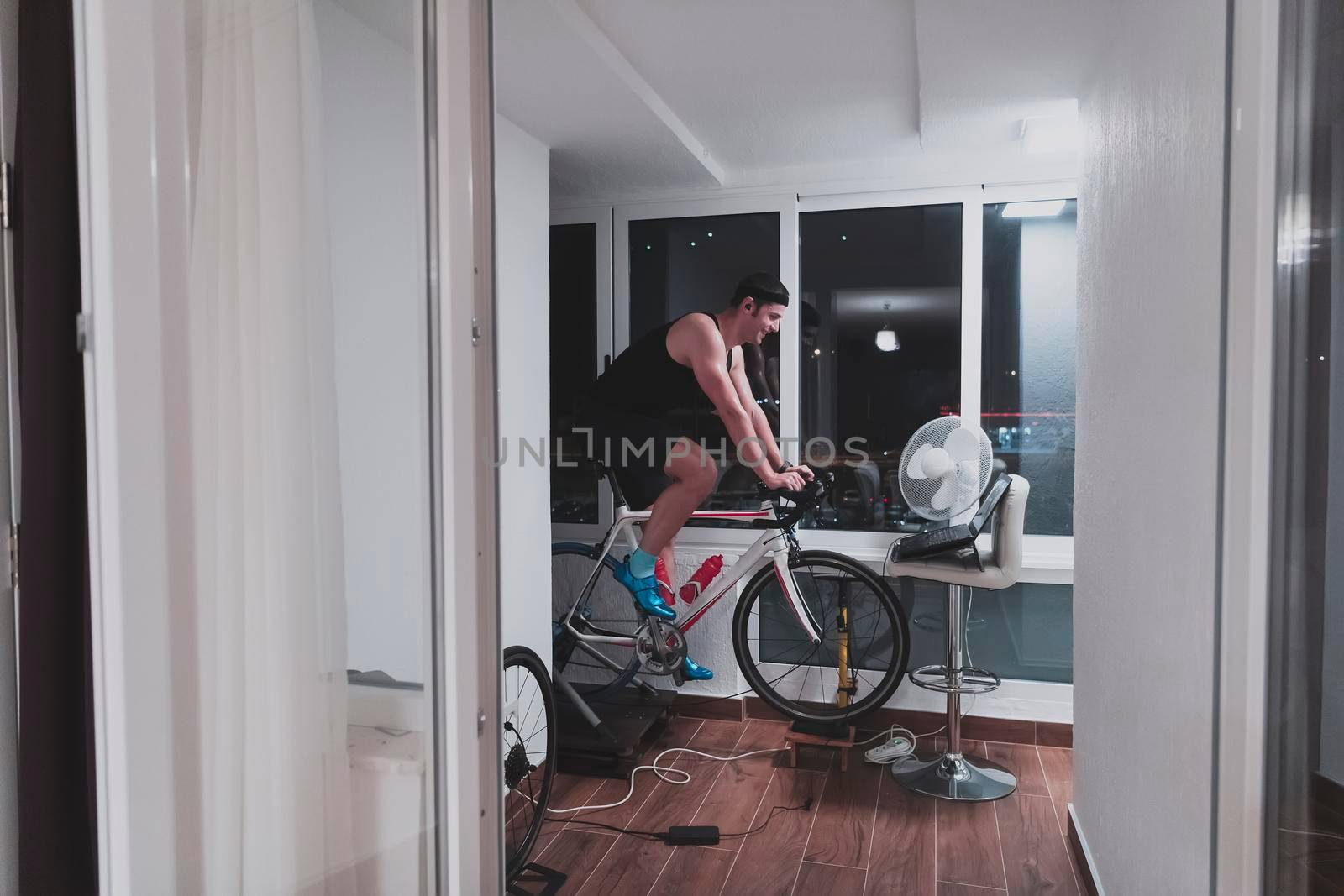 Man cycling on the machine trainer he is exercising in the home at night playing online bike racing game by dotshock