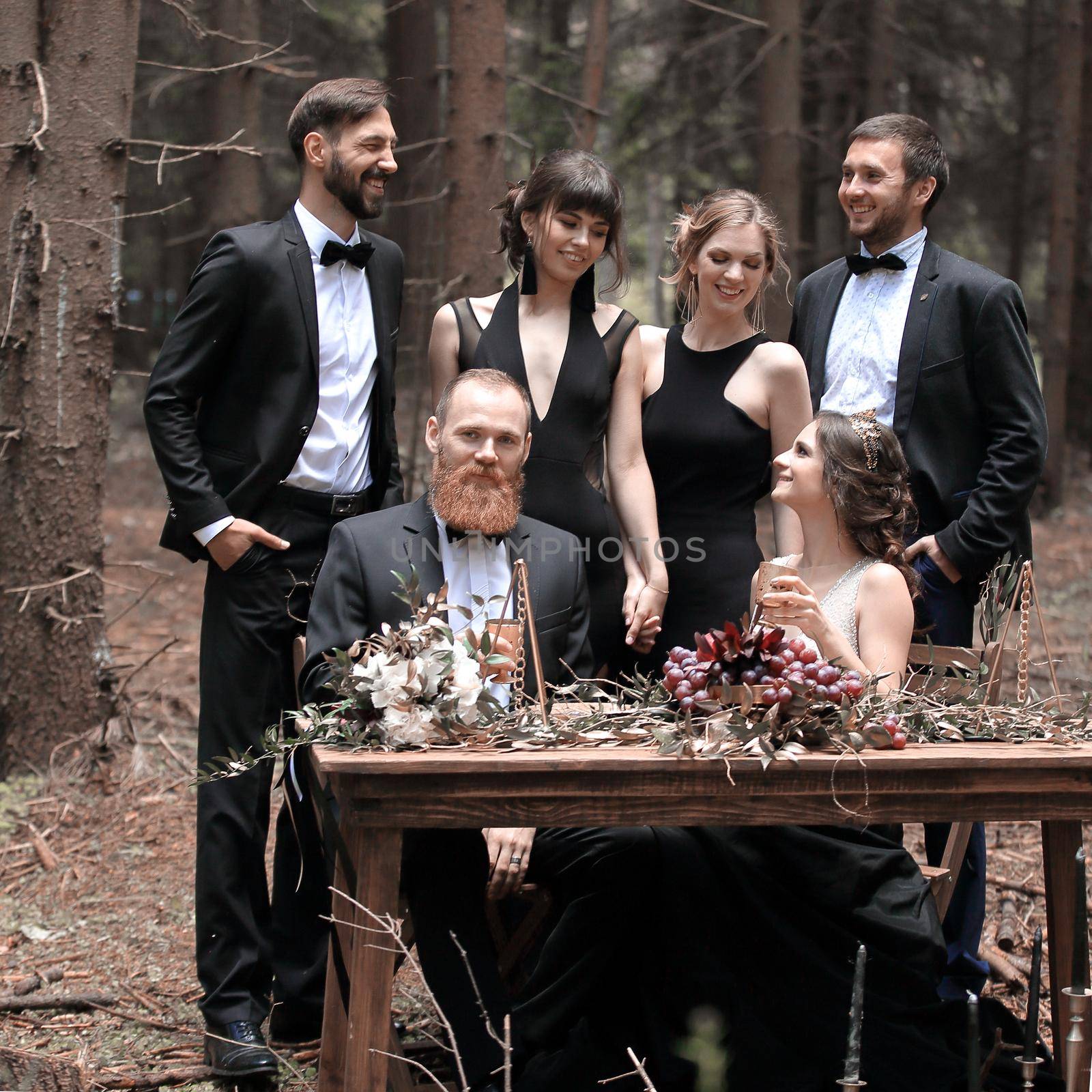 portrait of a guest and a couple of newlyweds near a picnic table in the woods by SmartPhotoLab