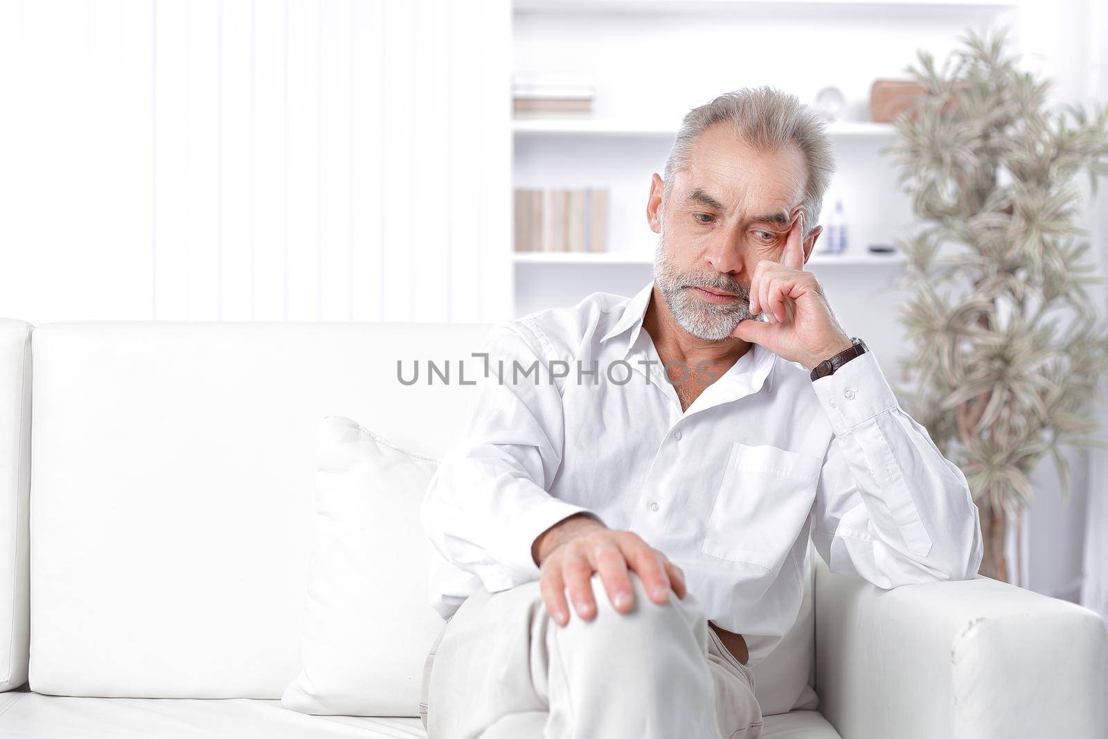 dreamy adult businessman sitting on sofa in office.