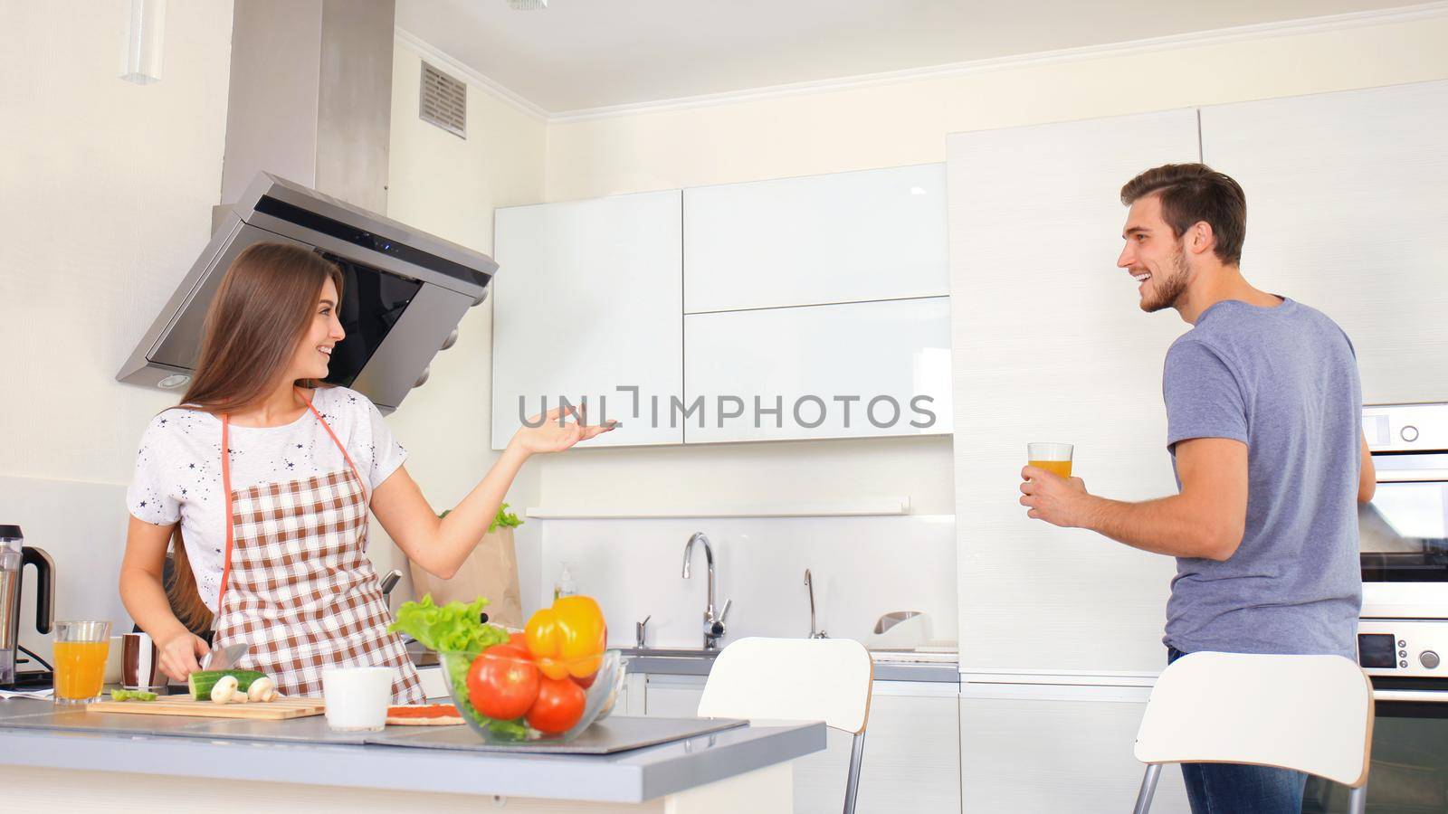 Portrait of happy young couple cooking together in the kitchen at home.