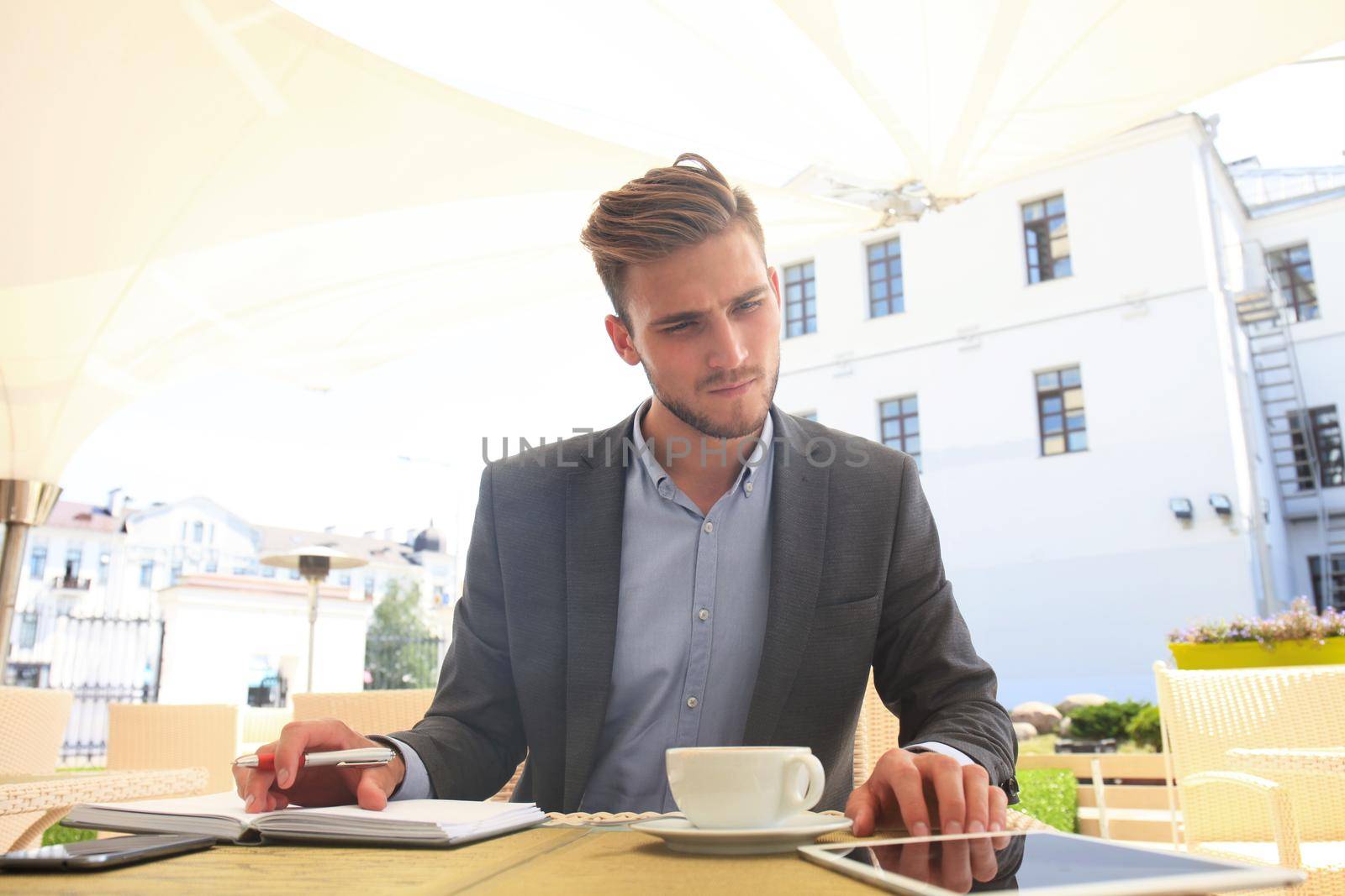 Businessman drinking coffee and reading news in cafe.