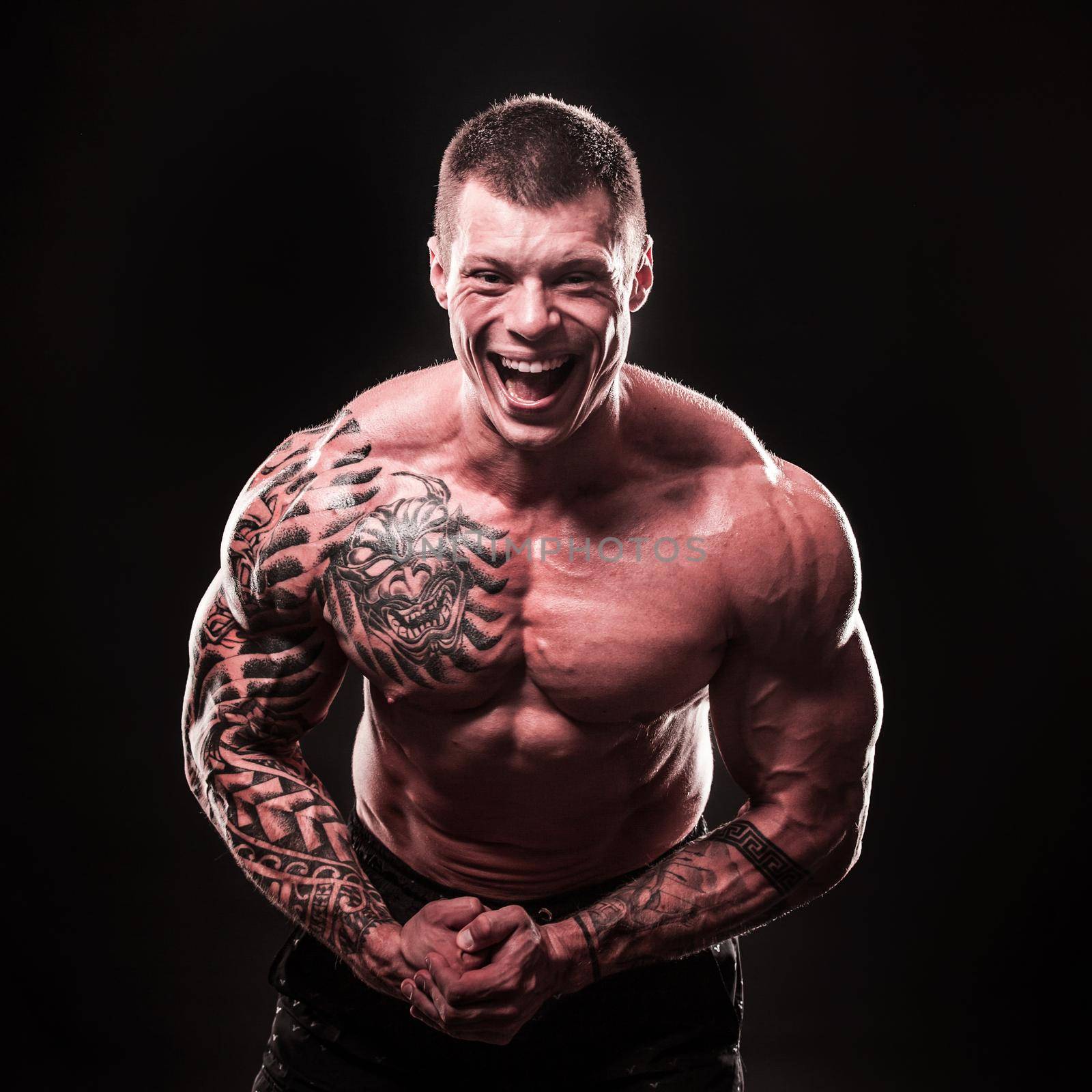 portrait of a cheerful muscular male bodybuilder.isolated on black background