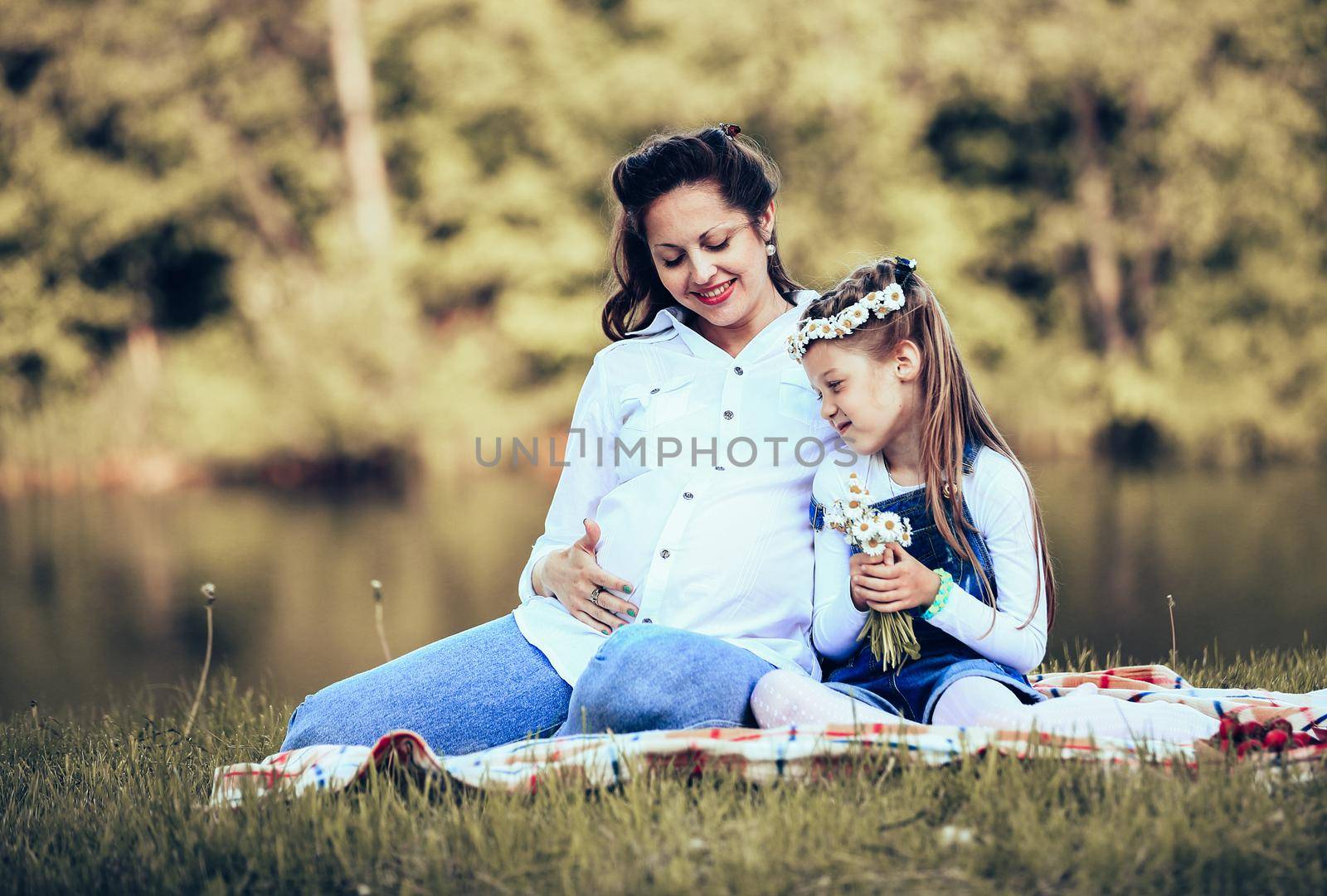 pregnant mother and little daughter having a picnic in the Park on a Sunny day. the photo has a empty space for your text