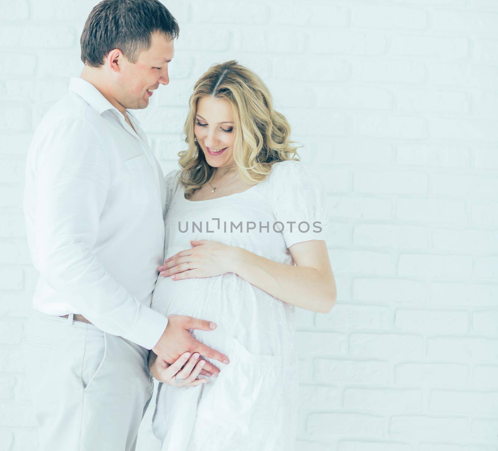 beautiful pregnant woman and man white brick background