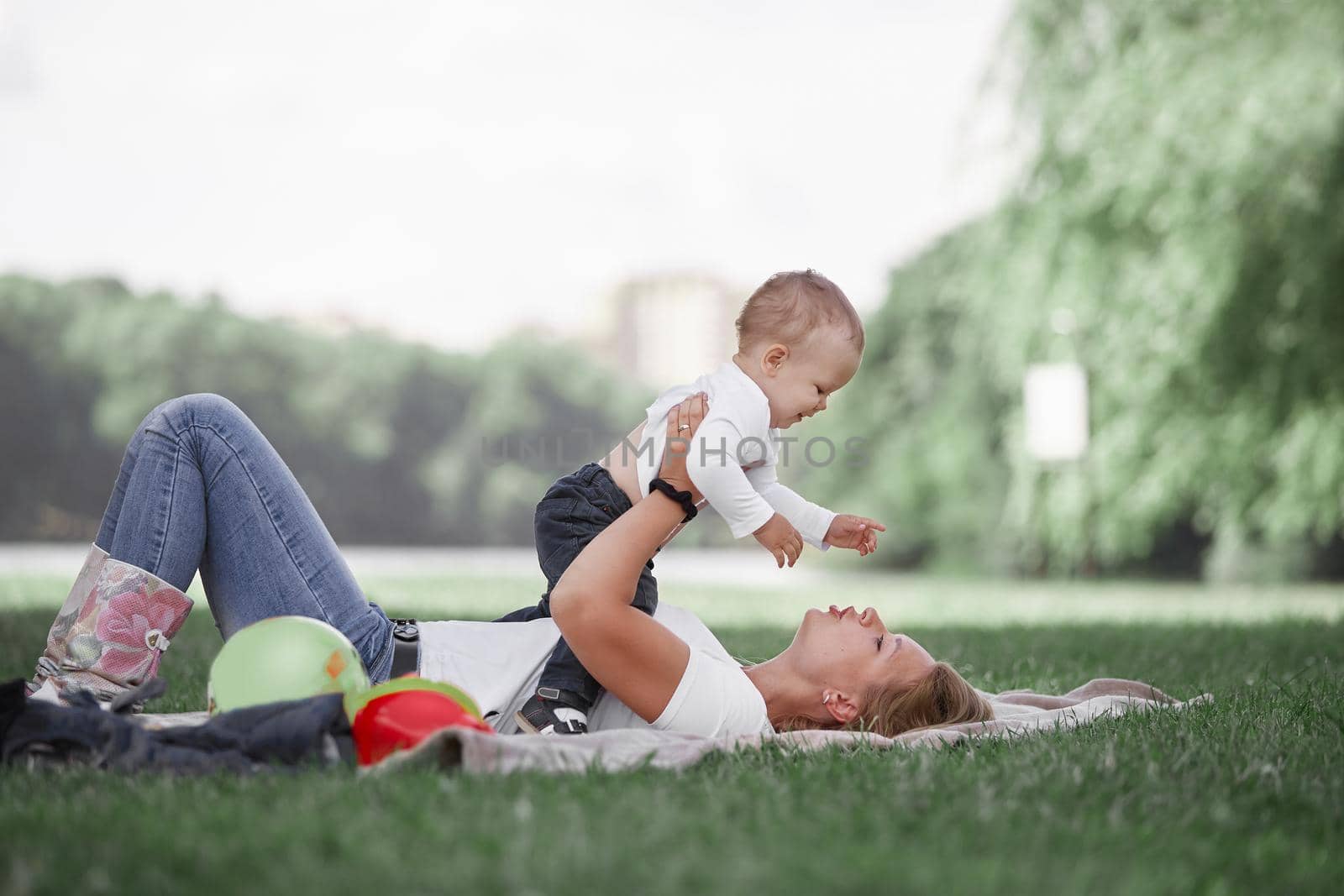 mom and her little son play together, lying on the lawn . photo with copy space