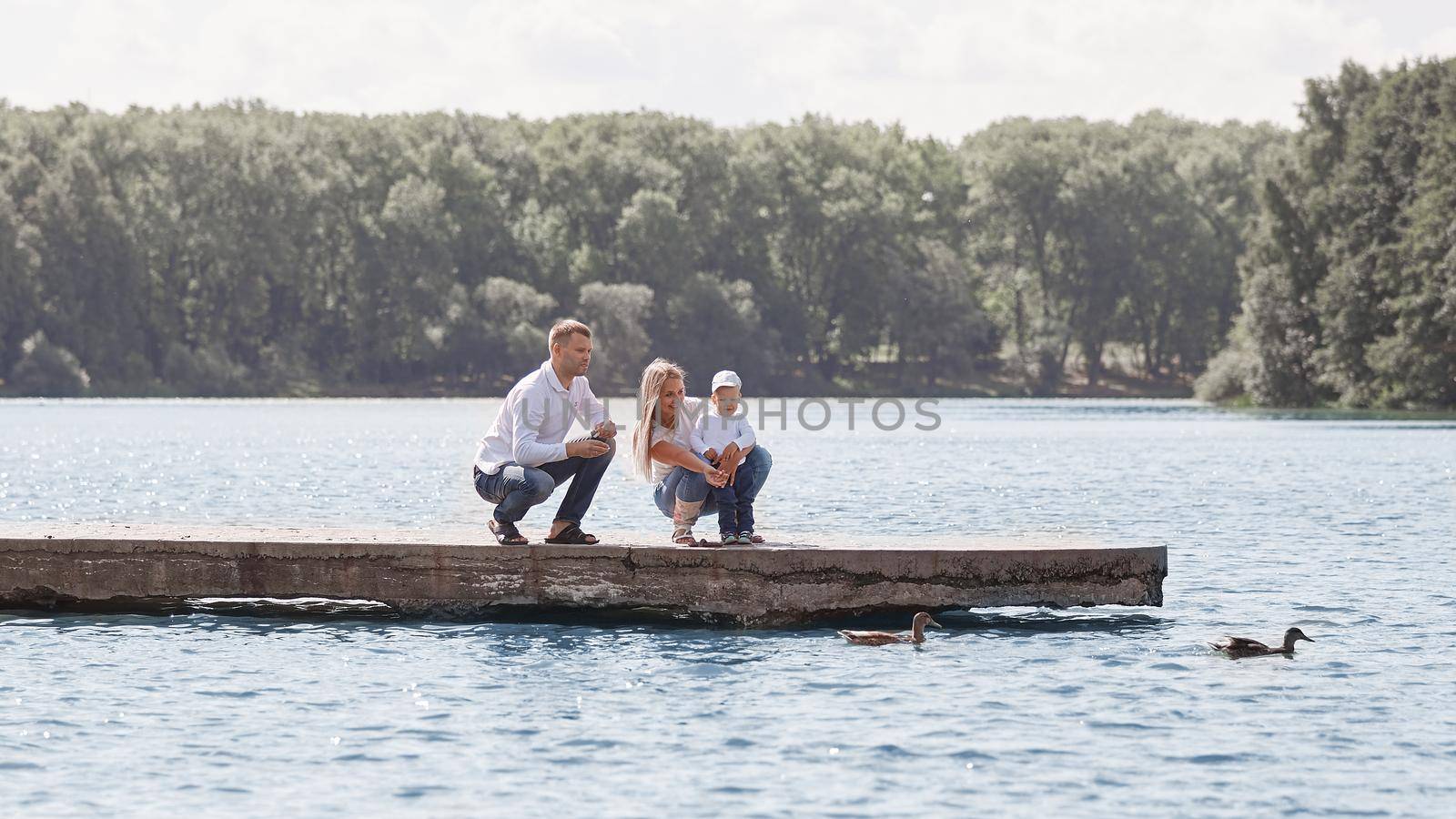 parents with their little son on a walk near the lake. people and nature