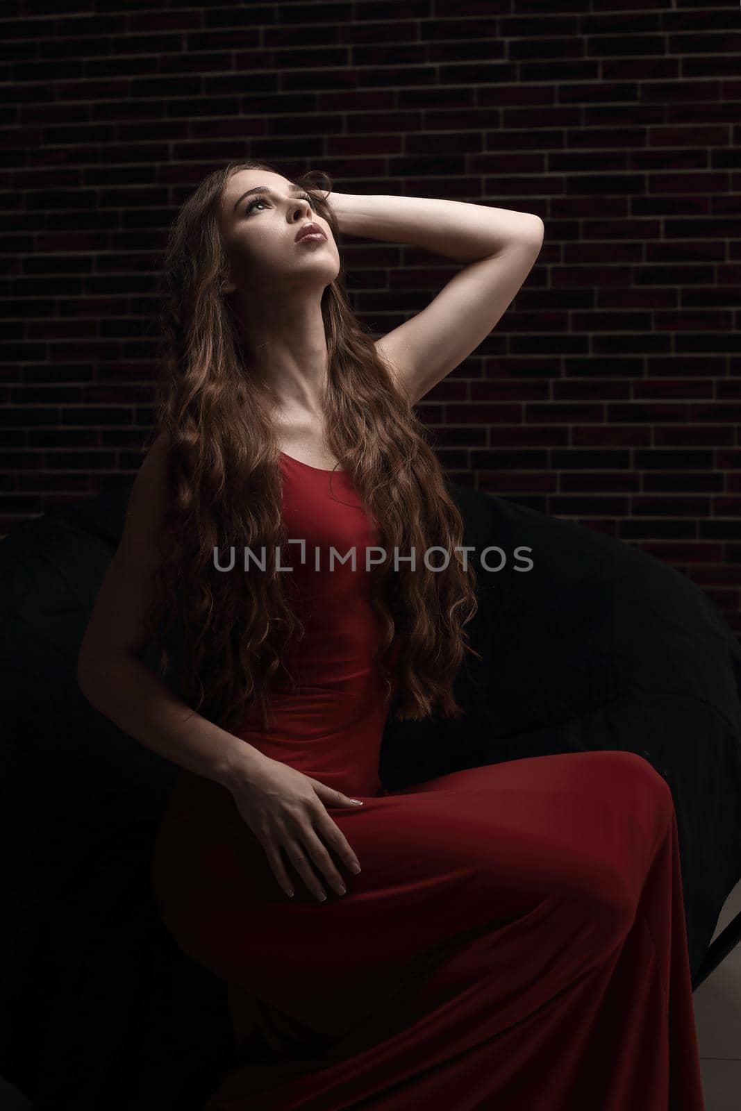 stylish young woman in red dress sitting in a chair.