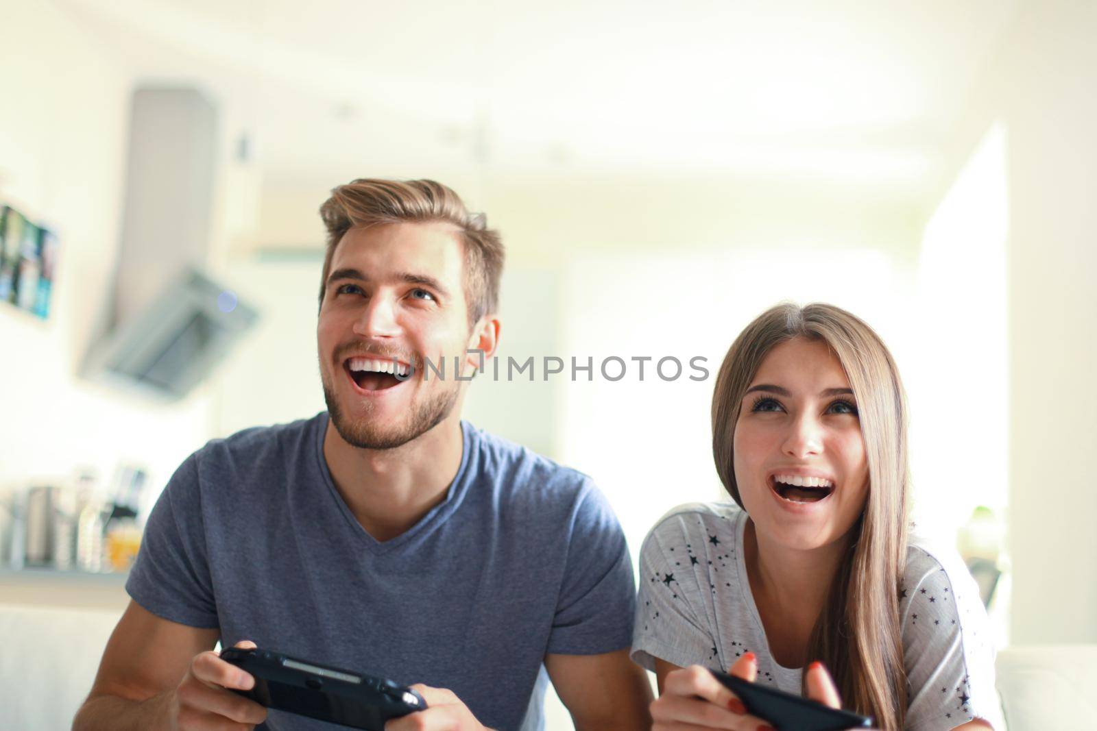 Young couple having fun playing videogame at home by tsyhun