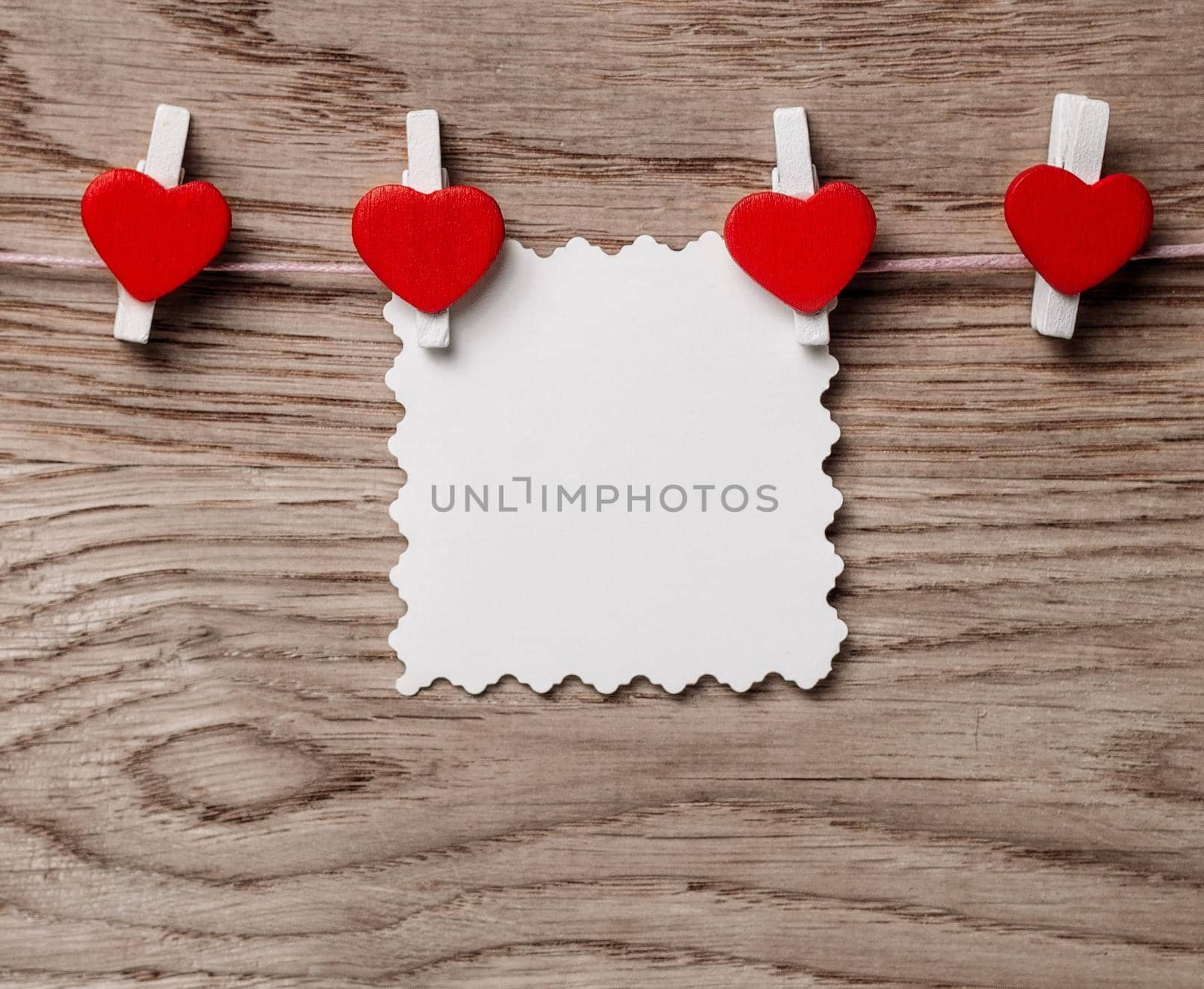 hearts and blank note on the clothespin on wooden background. photo with copy space