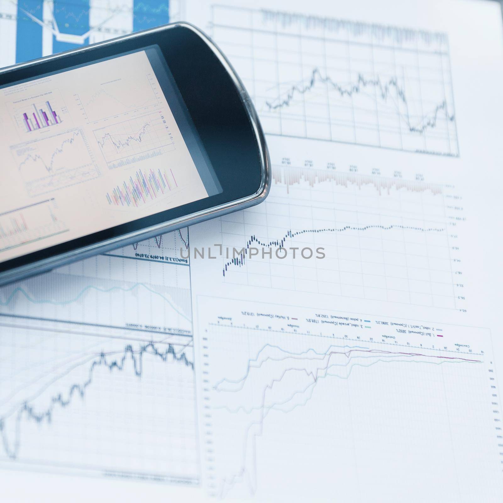 mobile phones and charts of financial growth on the desktop by SmartPhotoLab