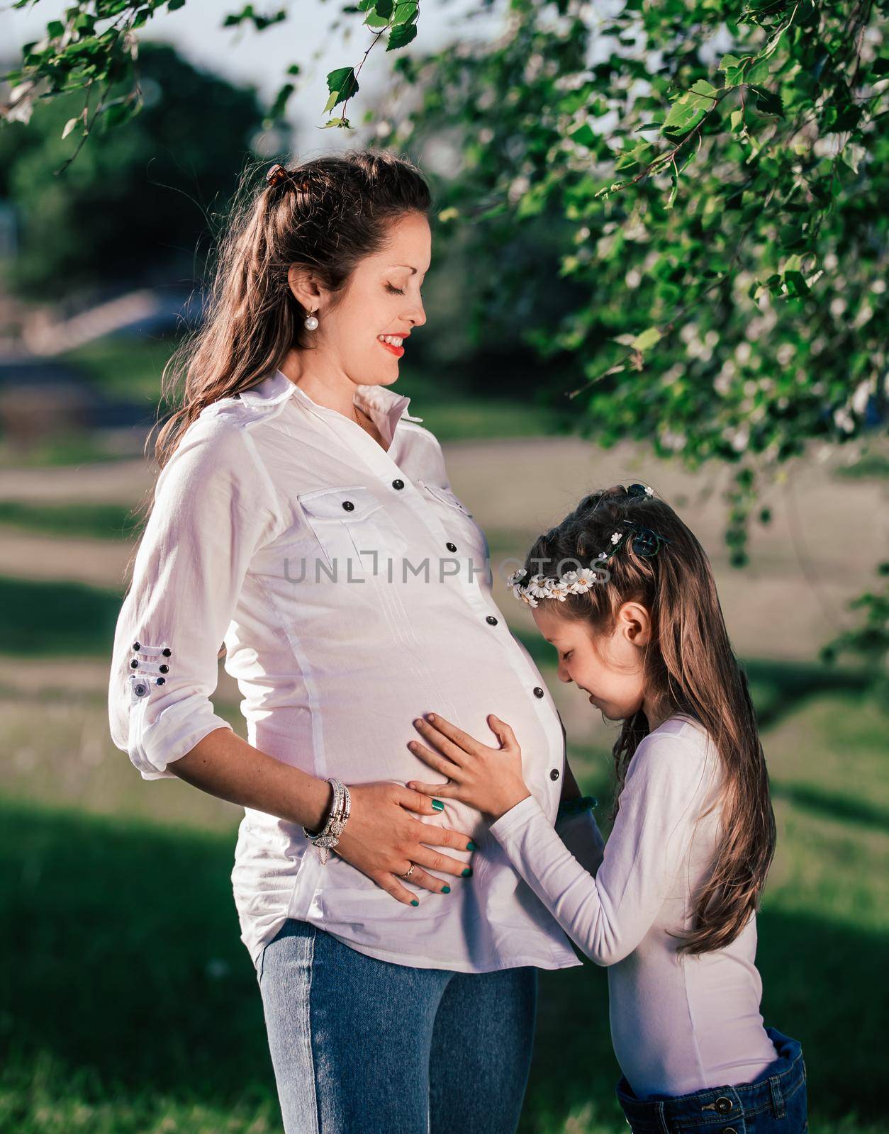 little girl and her happy pregnant mom on a walk in the summer Park by SmartPhotoLab