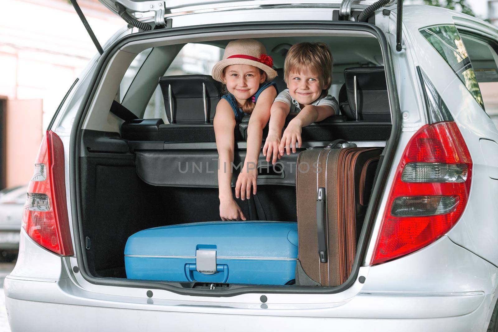 little brother and sister sitting in the back of a car. by SmartPhotoLab