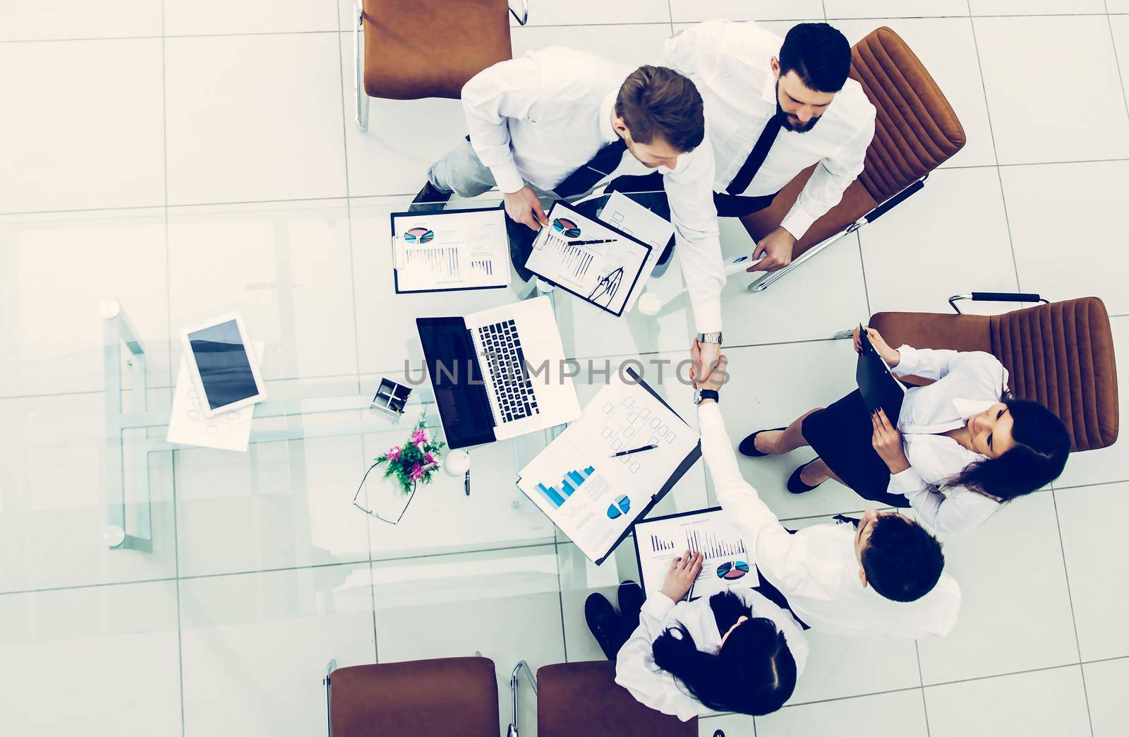 top view :successful business team shaking hands with new business partners after the conclusion of the financial contract in the conference room.the photo has a empty space for your text