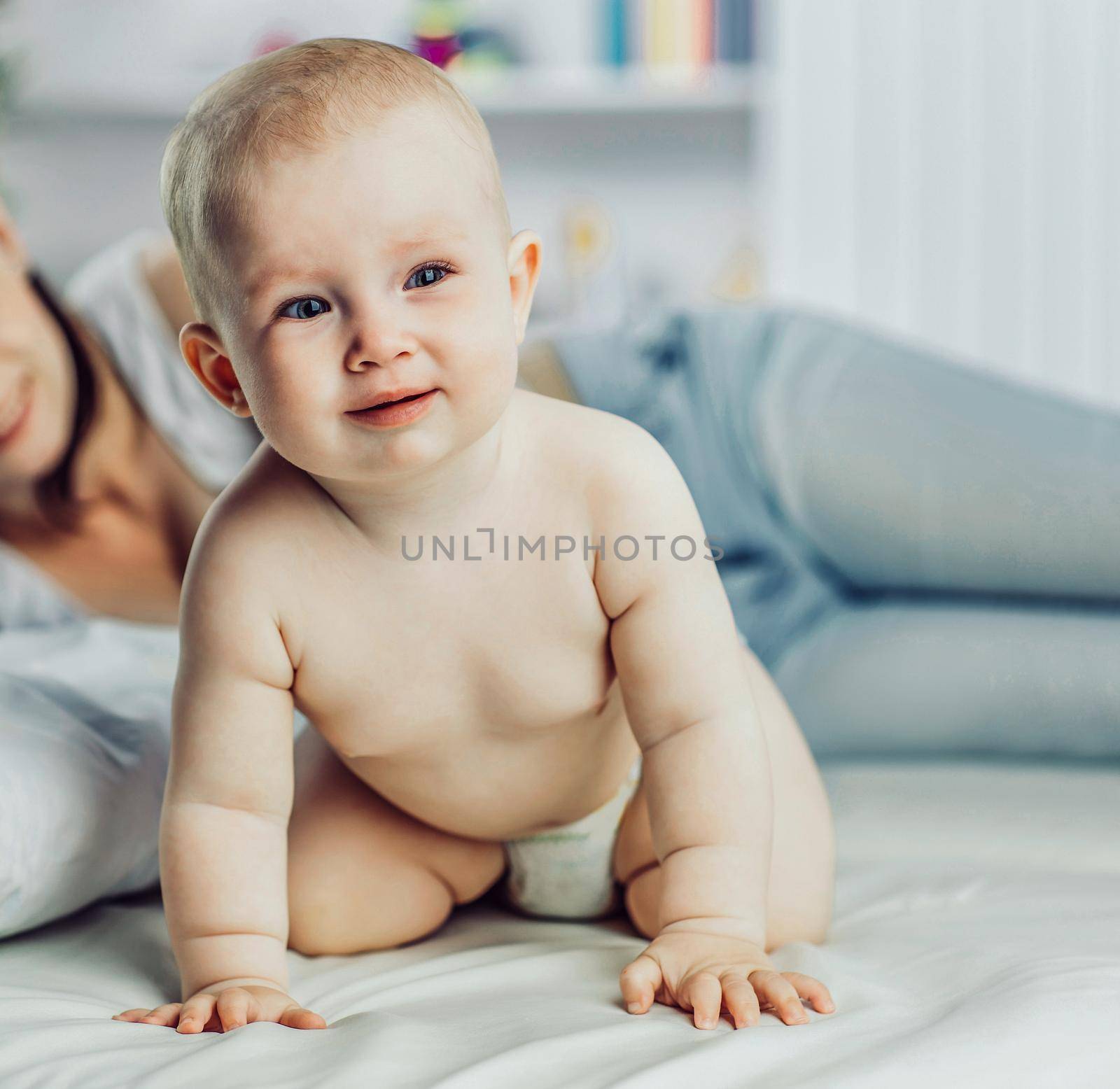 happy mother and year-old baby playing on bed in bedroom