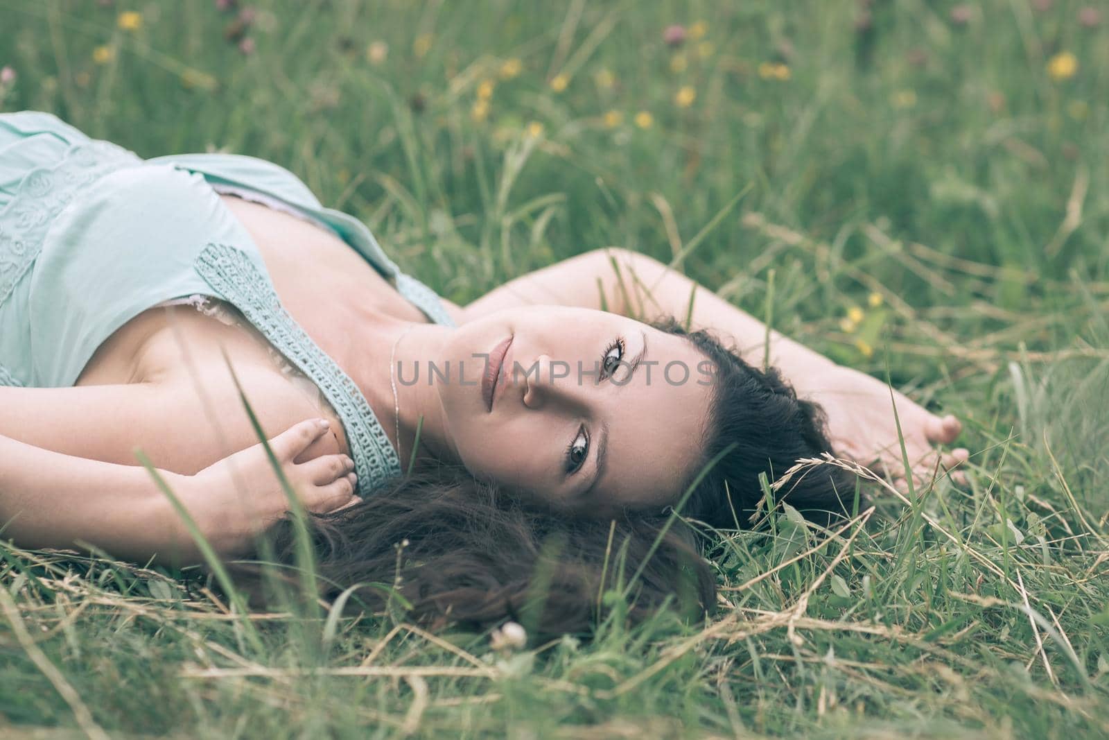 charming young woman relaxing in the meadow on a summer day. photo with copy space