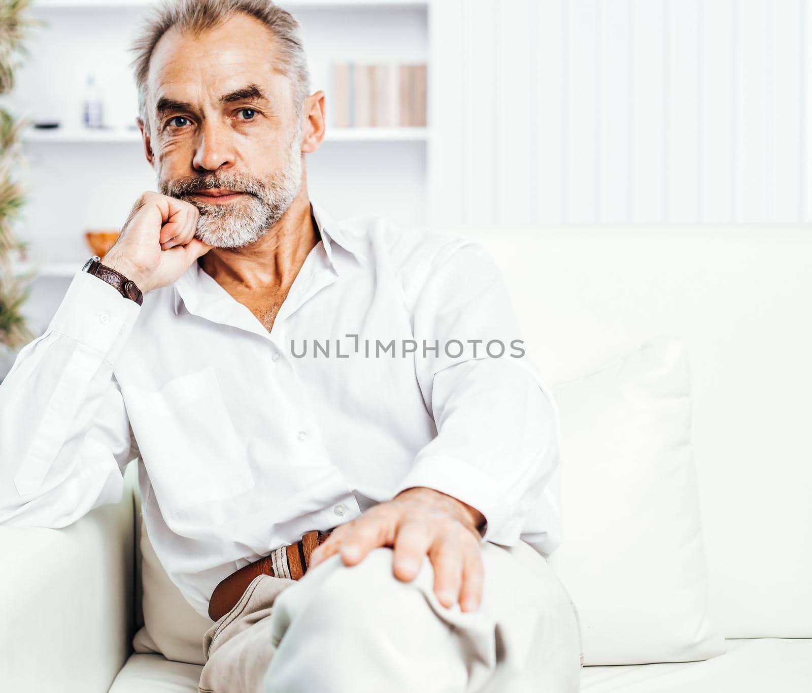 confident businessman sitting on couch in bright office. the photo has a empty space for your text